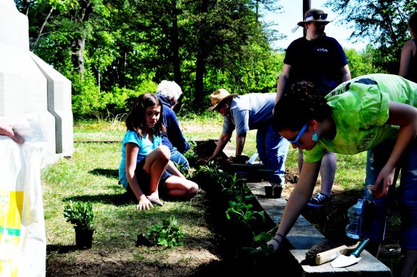 Nelda Coulter-Smith, Lydia Monroe, Angela Lavoy, Alyssa Boehm and Savannah Smith place flowers around the monument base.