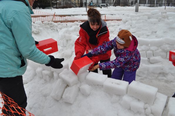 Mia Greenlaw gets some help from volunteer Michelle Krutsinger as they add a snow brick to the sculpture artist in residence Tim Gaudreau conceived.