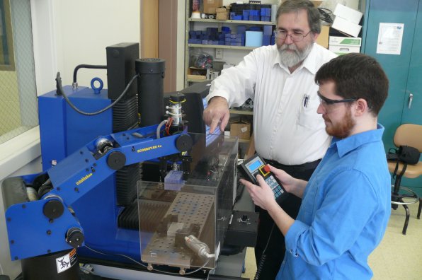 A student learns to program an industrial robot under the watchful eye of Prof. Robert Arredondo at NHTI.