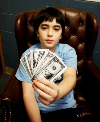 10-year-old Jacob Kenneally flashes some of the Club bucks (emblazoned with the faces of Club counselors) that he earned for doing his homework.