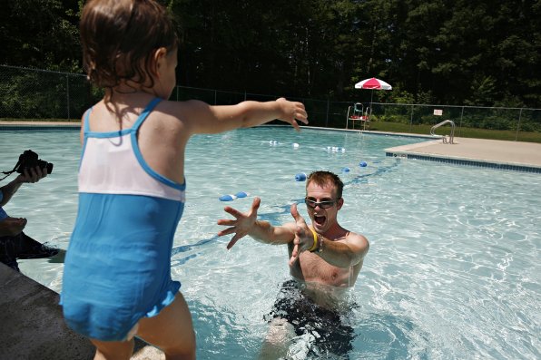 Sampson Raine, right, motions for his daughter Hadley, 2, to jump into the water during swimming lessons at Garrison Park, July 13, 2011.