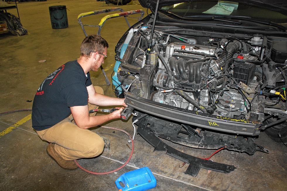 Nate Cushman works to remove the front bumper support of an SUV. (JON BODELL / Insider staff) - 
