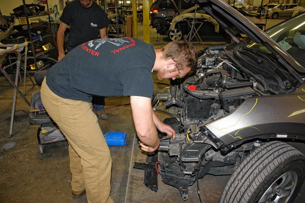 Nate Cushman works on the front end of a damaged SUV. (JON BODELL / Insider staff) - 
