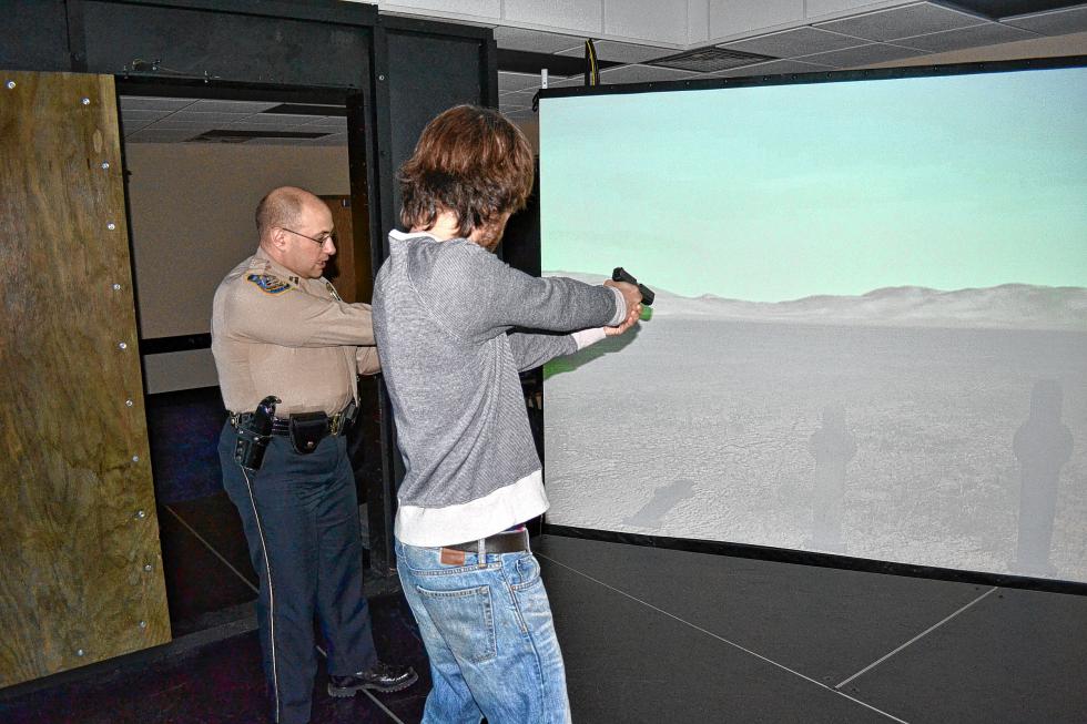 Capt. Mark Bodanza shows me proper aiming technique as I shoot at some targets in the simulator at the police academy in Concord last week. I nailed them all, in case you were wondering. (TIM GOODWIN / Insider staff) -