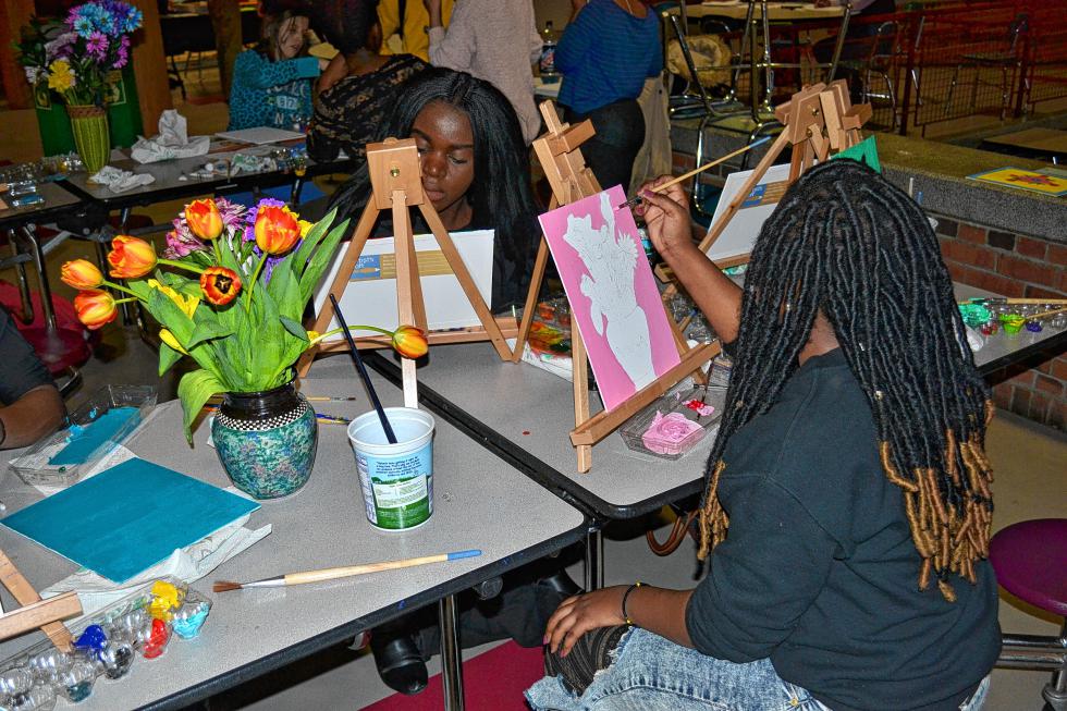 Concord High sophomores Vanessa Uwera (facing) and Rebecca Kado paint their version of the fresh flowers last week. There were also cookie bars to munch on while they painted. (TIM GOODWIN / Insider staff) -