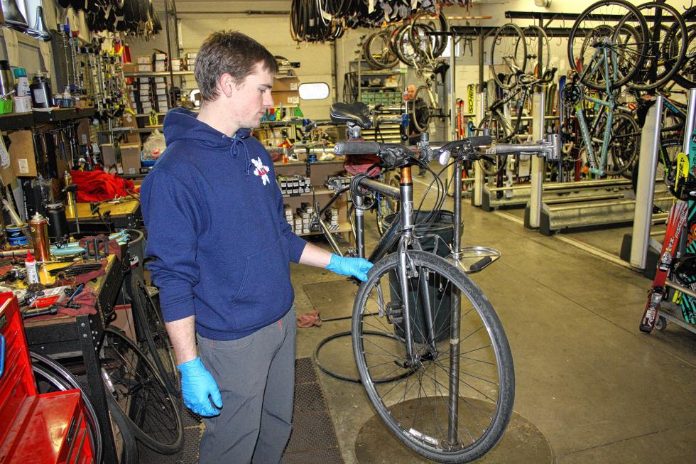 Finn Westbrook inspects the front tire of a bike at S&W Sports in Concord last week. If your bike has been sitting out in the garage since August, you'll want to make sure your tires haven't dried out and cracked. (JON BODELL / Insider staff) -