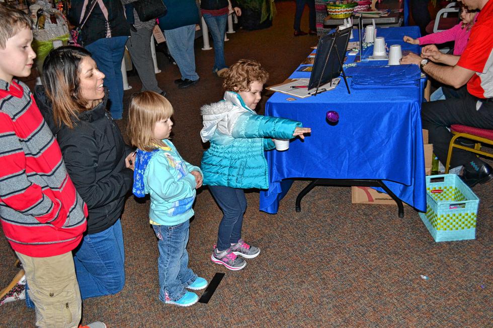 Delia Towne, 4, tosses an egg, while her sister, Julia, brother, Ethan, and mom, Melinda, look on. (TIM GOODWIN / Insider staff) -