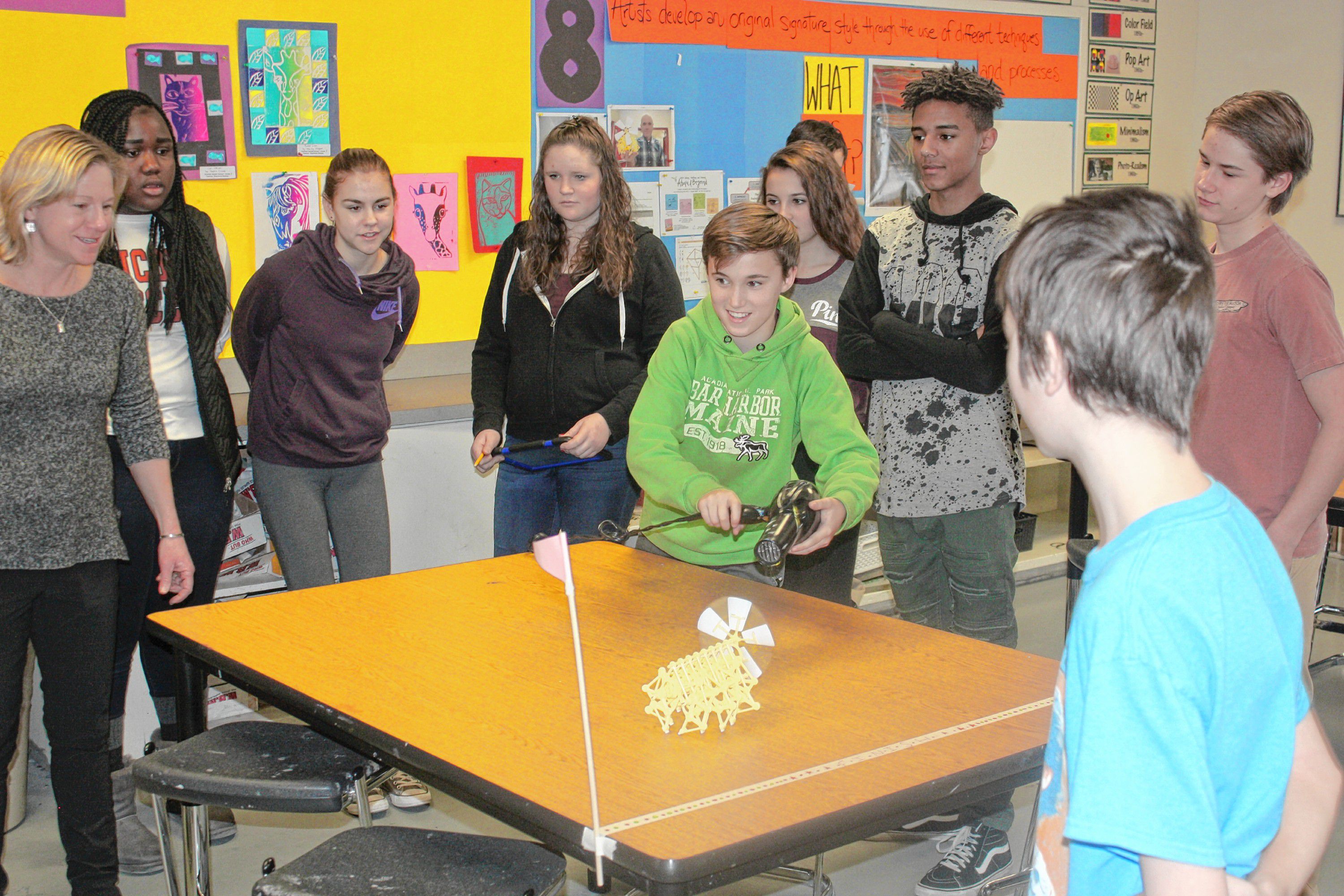 Cameron Detwiller (center) uses a hair dryer to power his Strandbeest while (from left) teacher Stephanie Bednaz, Rose Fornor, Lorelei Ford, Kathleen Shoemaker, Ava Corrente, Terrel Dixon, Nathaniel Bowers and Steven Martin look on during art class at Rundlett Middle School last week. The students spent the previous week or so building the Strandbeest, and this shot was taken during a race against another team of students.(JON BODELL / Insider staff)