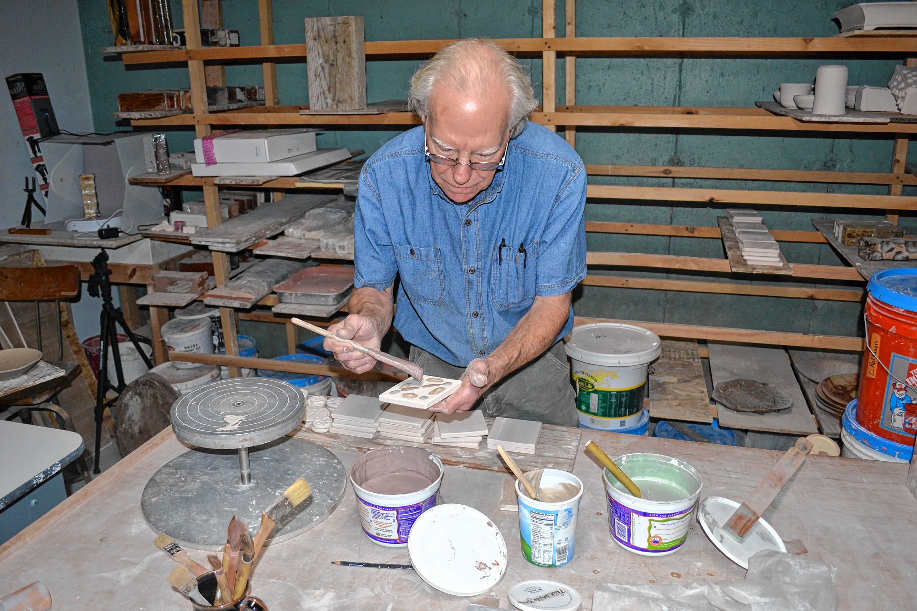 Andy Hampton of Hampton pottery paints tiles, a hands on craft he will offer at his home studio during N.H. Open Doors. TIM GOODWIN / Insider staff