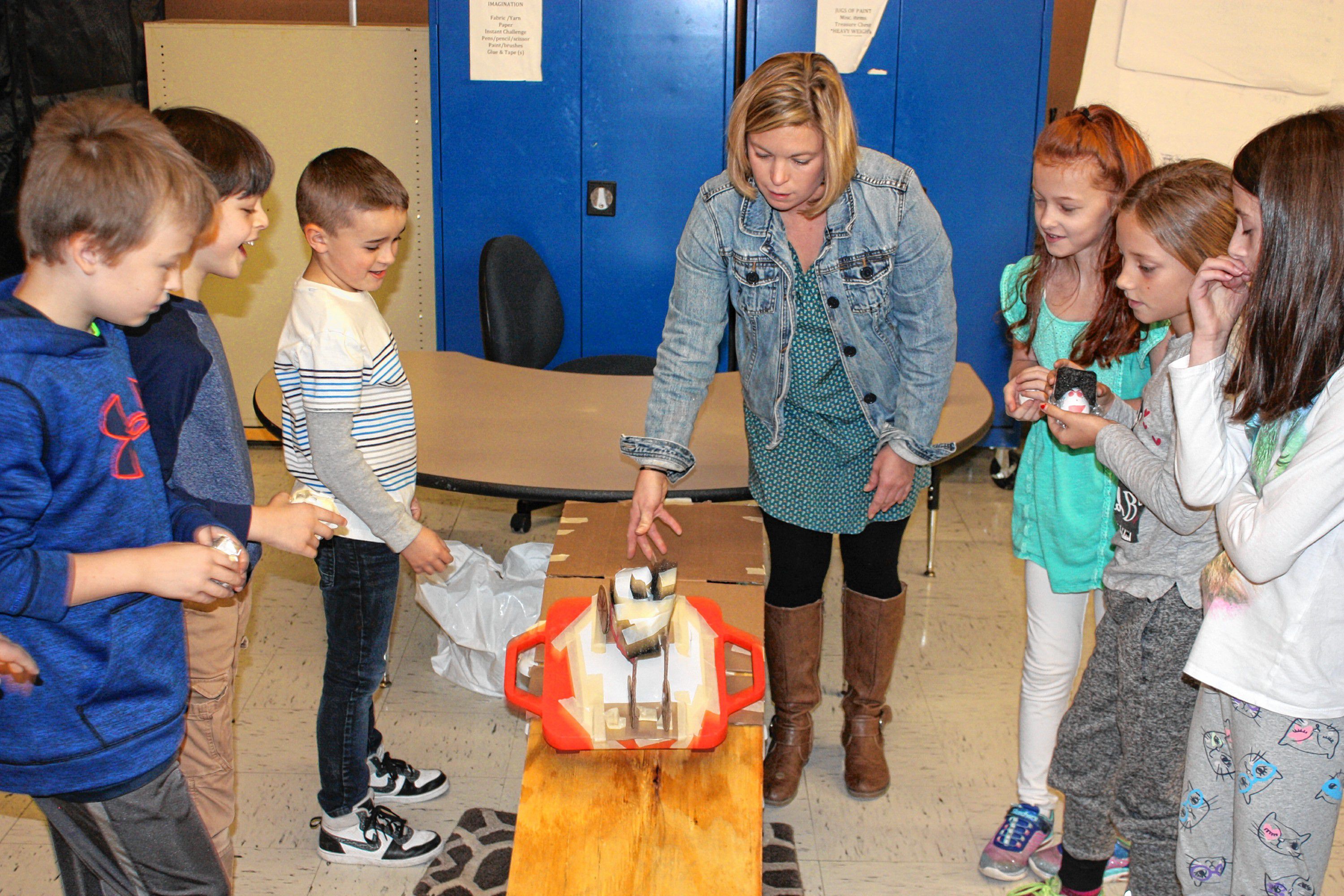 Bow Elementary School health teacher Jill Pelletier helps students from Ms. Gage's fourth-grade class test their egg helmets at the school last week. JON BODELL / Insider staff