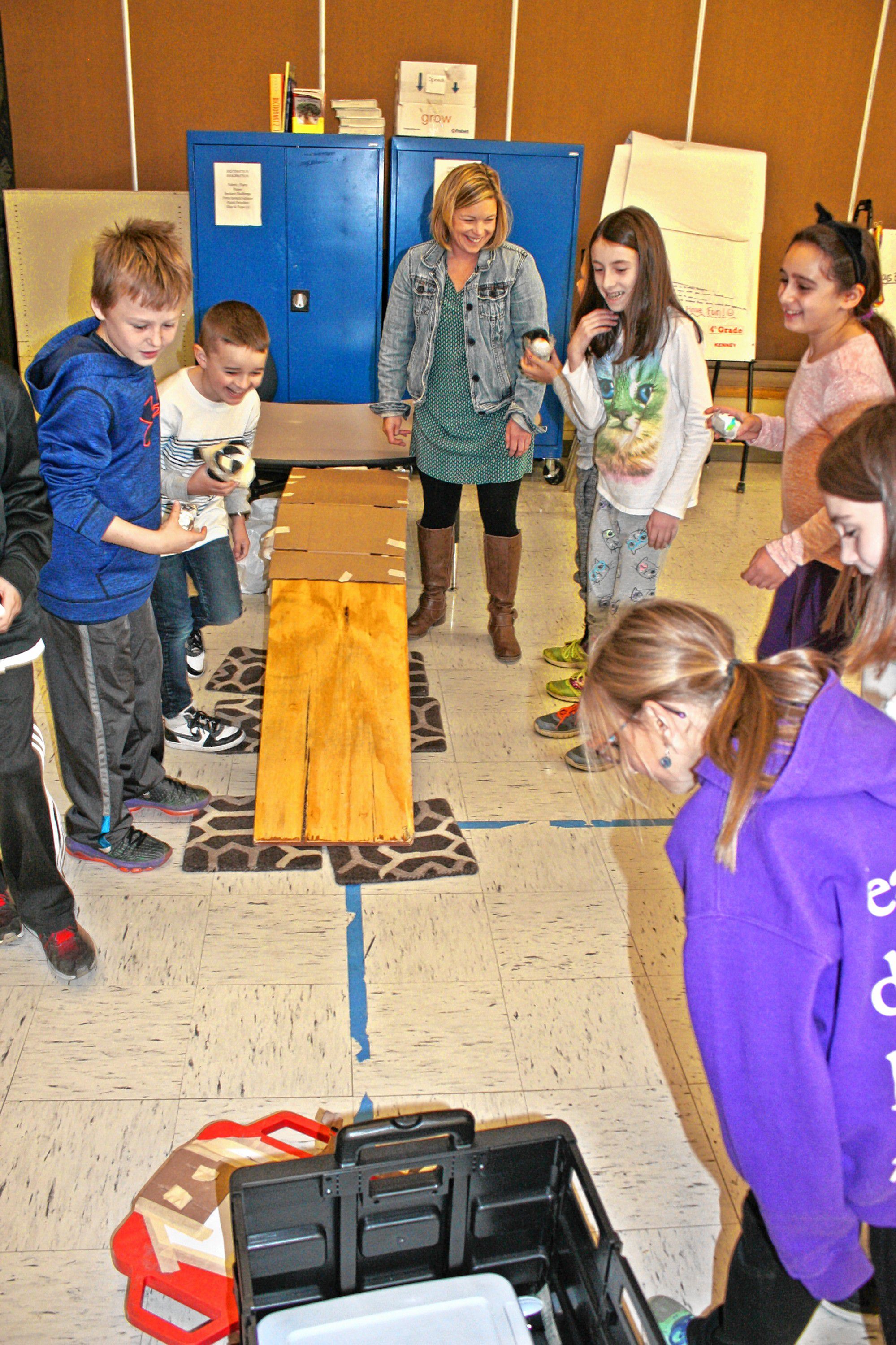 Bow Elementary School health teacher Jill Pelletier helps students from Ms. Gage's fourth-grade class test their egg helmets at the school last week. JON BODELL / Insider staff