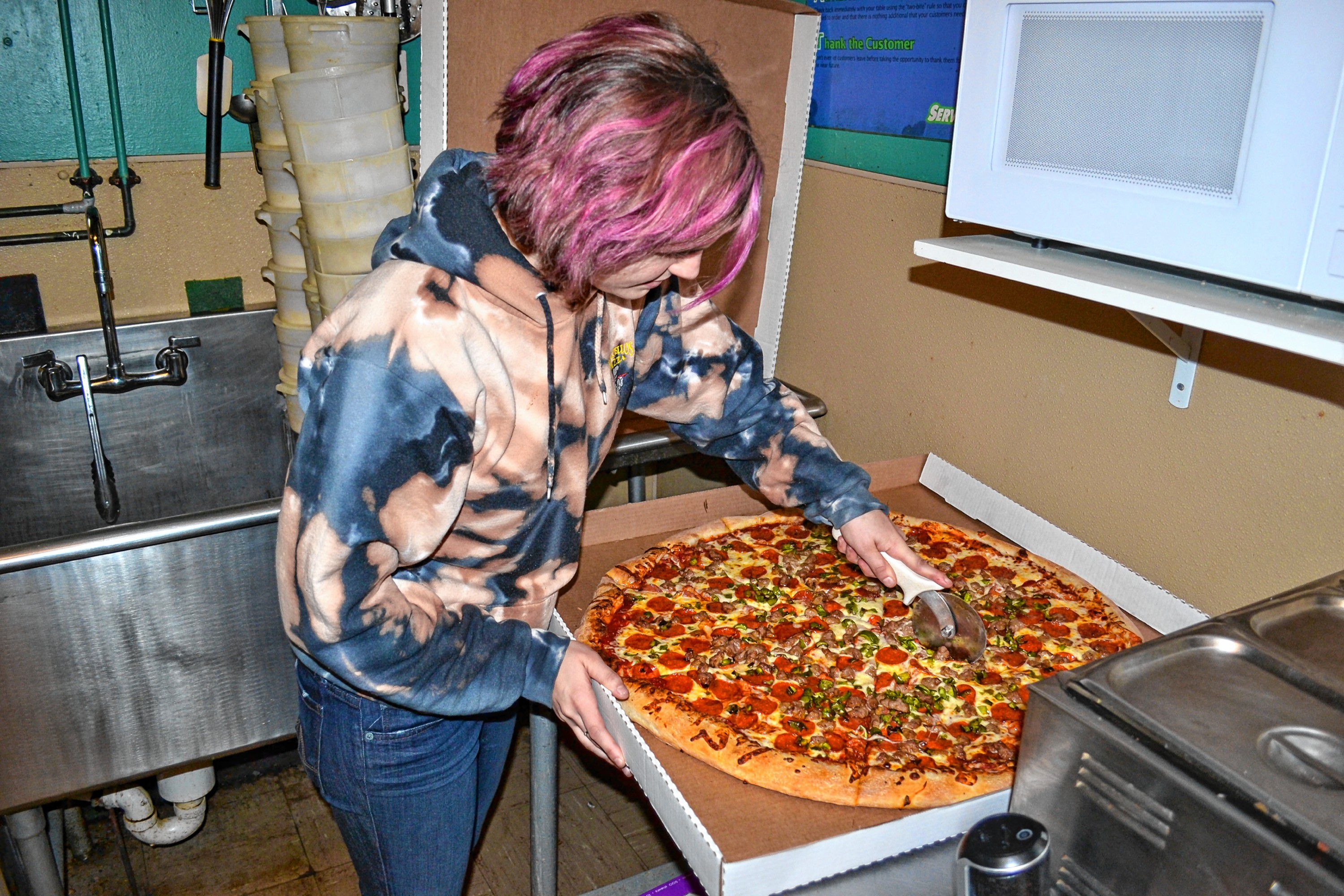 Rylee Orlosk cuts the 28 inch super dominator into 16 mouth watering slices. TIM GOODWIN / Insider staff