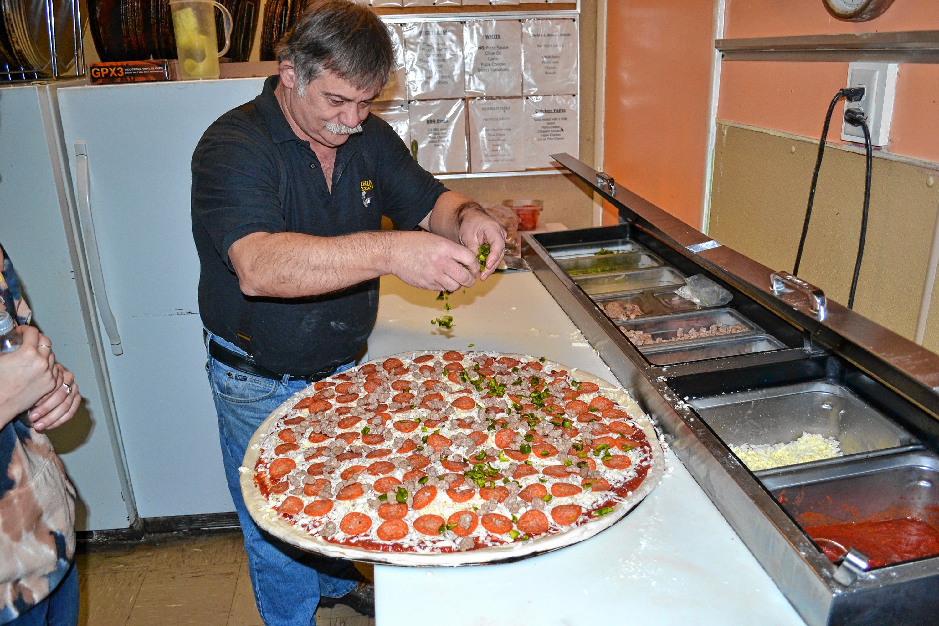 Donatello's owner Bob Boisvert adds green peppers to a super dominator. TIM GOODWIN / Insider staff