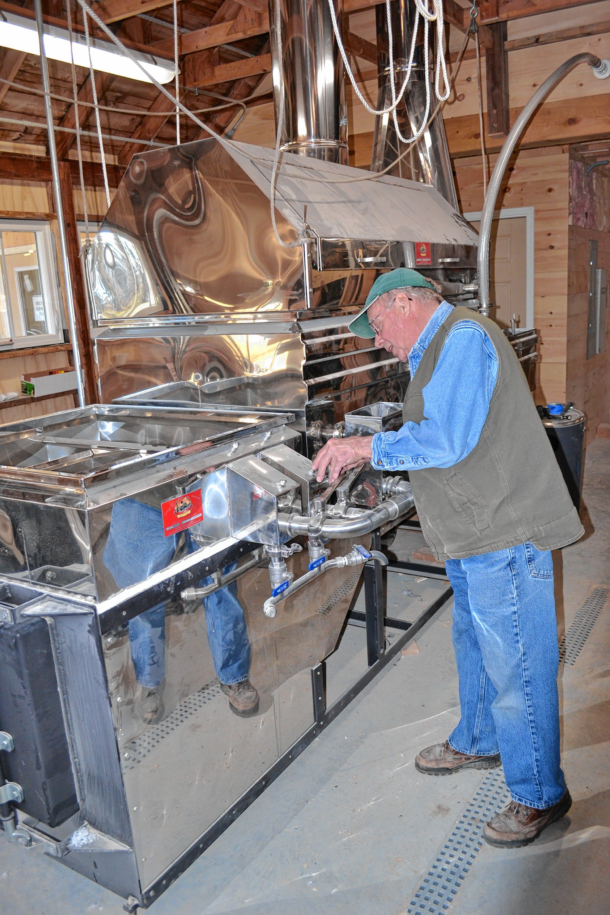 Mapletree Farm owner Dean Wilber installs a thermometer in the new evaporator that is the star of the show in his newly expanded sugarhouse. TIM GOODWIN / Insider staff