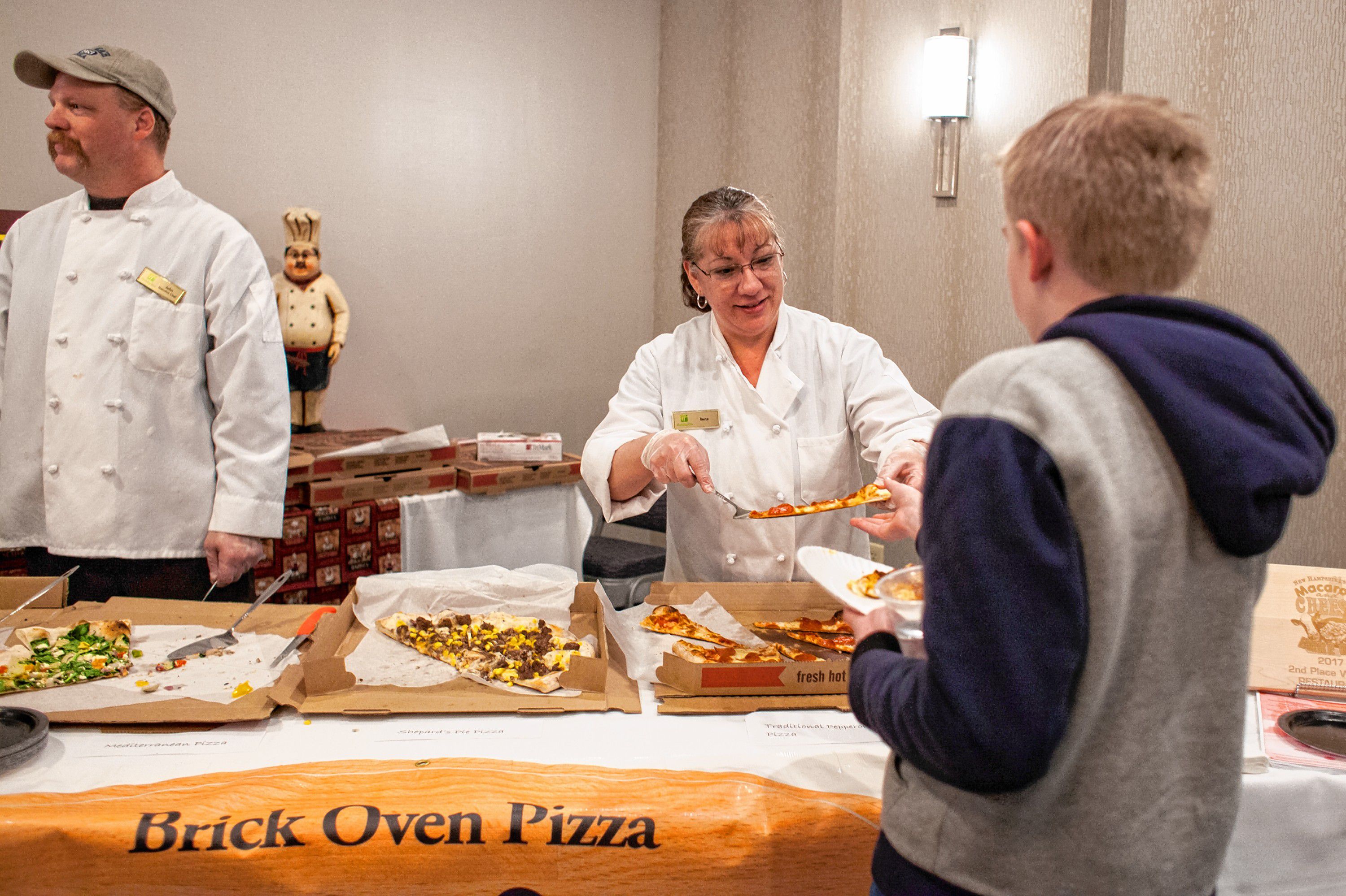 Rene Berube serves slices of EJ's on Main pizza during the Pizza Pie Showdown at the Holiday Inn in downtown Concord on Pi Day, Mar. 14, 2018. Proceeds from the event, hosted by the Concord Monitor and Insider, went to support the Friendly Kitchen. (ELIZABETH FRANTZ / Monitor staff) Elizabeth Frantz