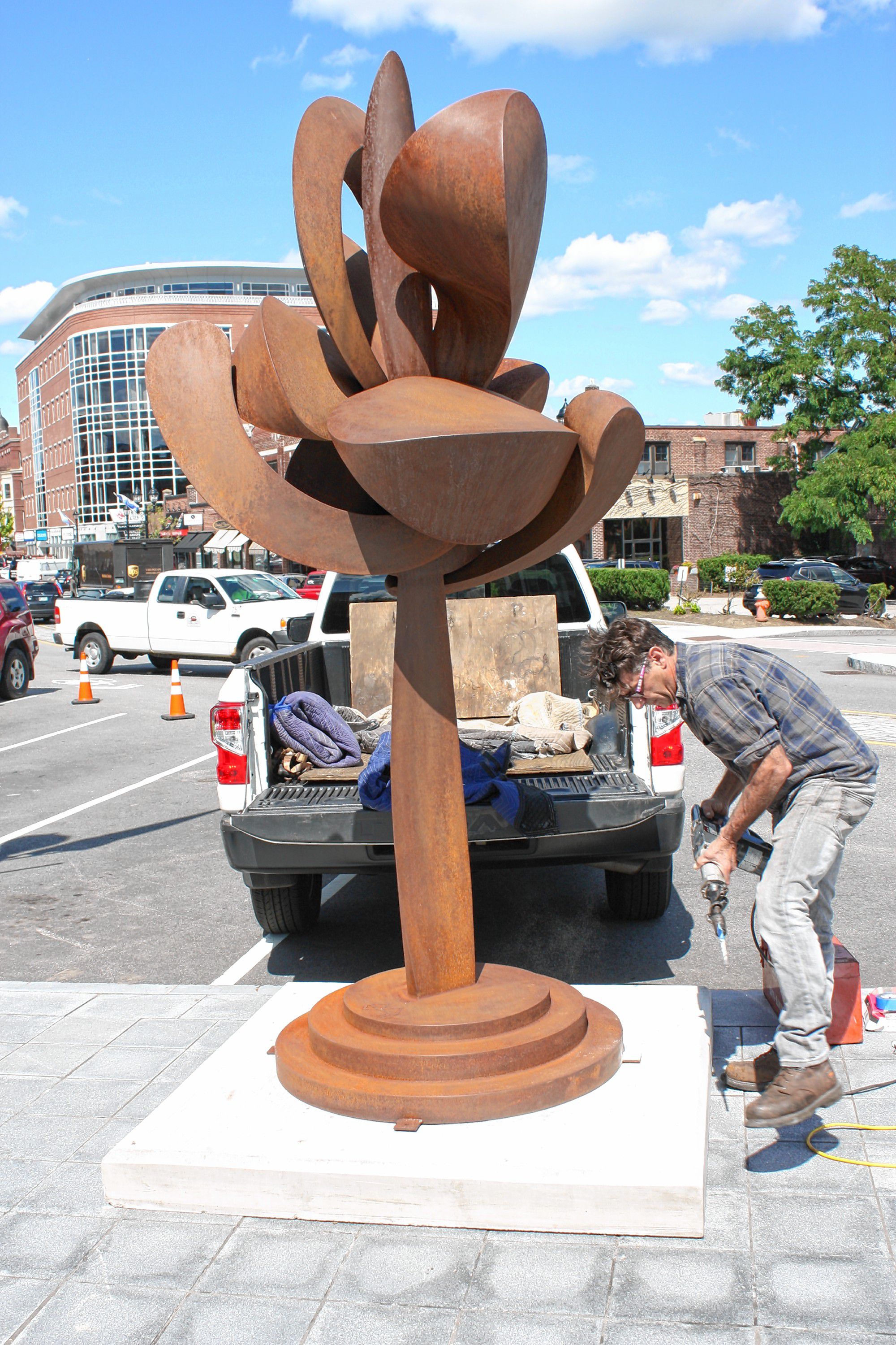 Artist David Boyajian of New Fairfield, Conn., works to install his sculpture "Unfurling With Seeds" at the intersection of South Main and Fayette streets last Thursday, a day in which two big sculptures were installed as public art in downtown Concord. JON BODELL / Insider staff