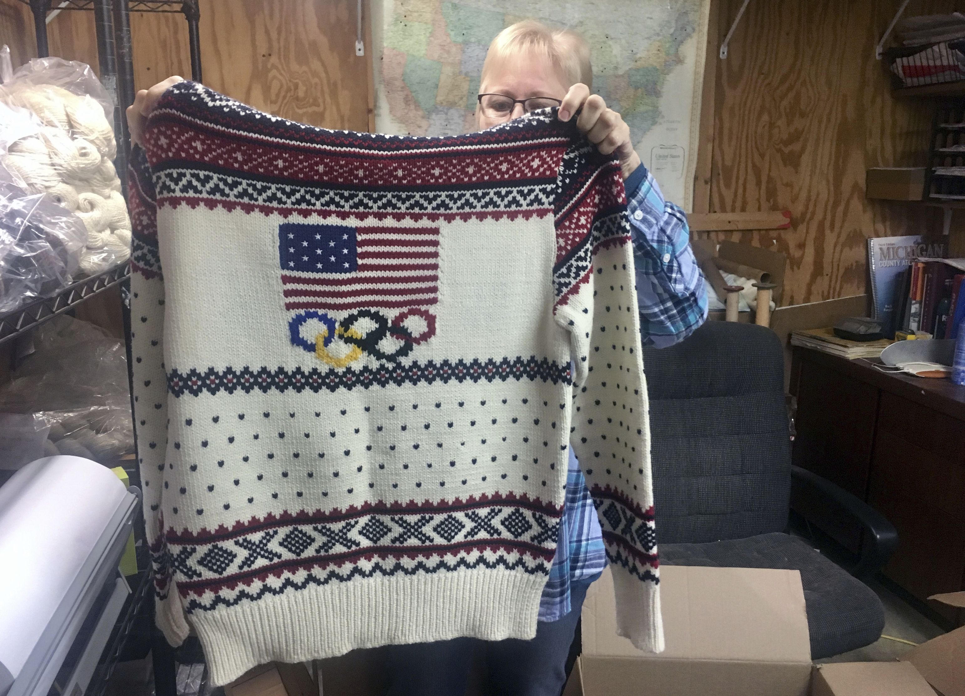 This Oct. 16, 2018 photo shows Debbie McDermott holding up the back side of a Ralph Lauren sweater in East Jordan, Mich., that athletes wore for the 2014 Winter Olympics closing ceremony. The sweater was made using Shepherd's Wool, one of Stonehedge Fiber Mill's yarn lines. (Shireen Korkzan via AP)  Shireen Korkzan