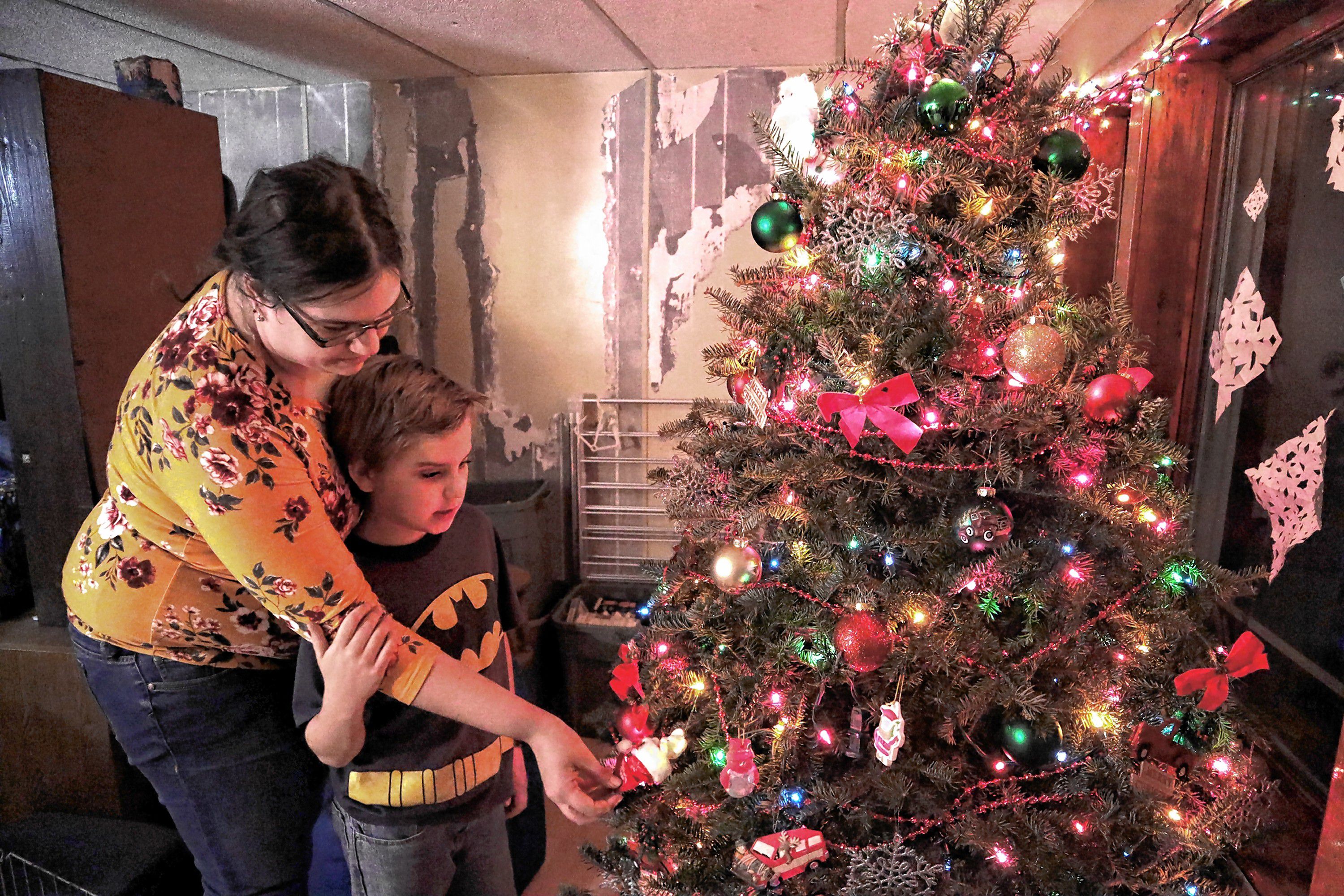 Shaye Campbell, 9, and his stepmother, Vicki Cobb, look at ornaments on the Christmas tree in their new apartment in Chichester last Wednesday. BELOW: The family was living in a tent after their home burned down in September.