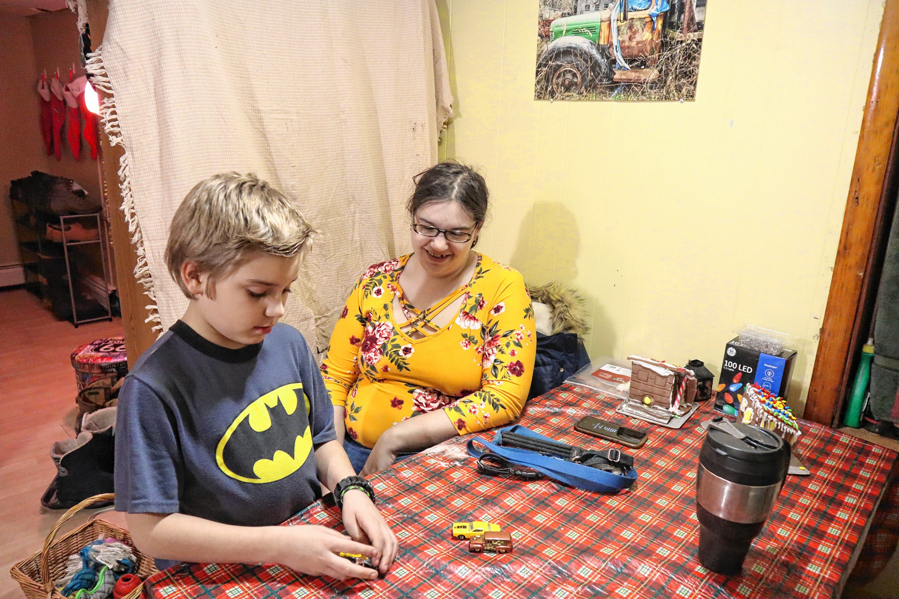 Shaye Campbell, 9, plays with toy cars at his family’s kitchen table next to his father’s girlfriend, Vicki Cobb. 