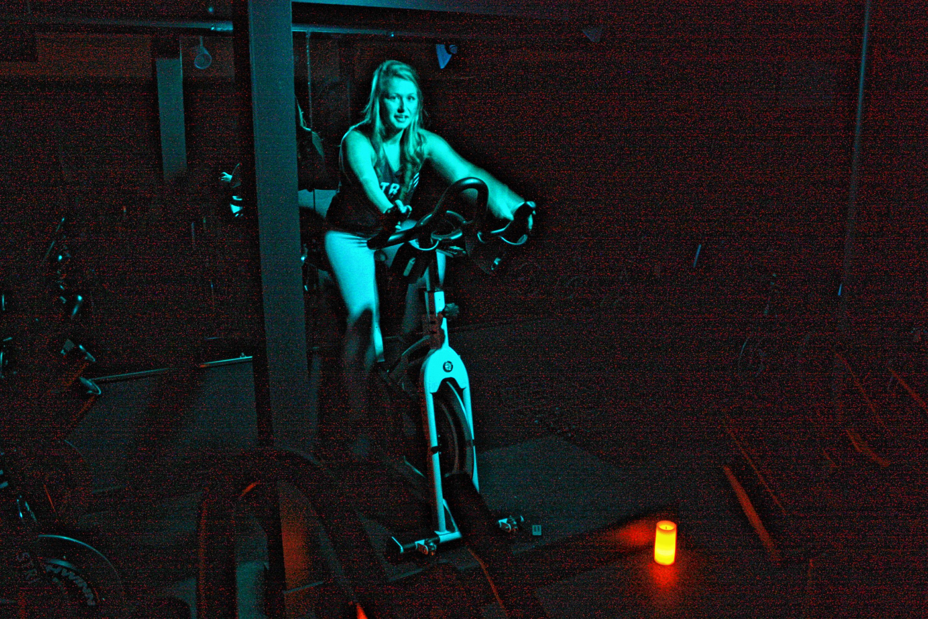 Meagan Ferns, owner of Strive Indoor Cycling, demonstrates how she leads her cycling classes at the studio. She likes to kill the main lights, leaving just a colored lamp on to illuminate her at the front of the class. JON BODELL / Insider staff