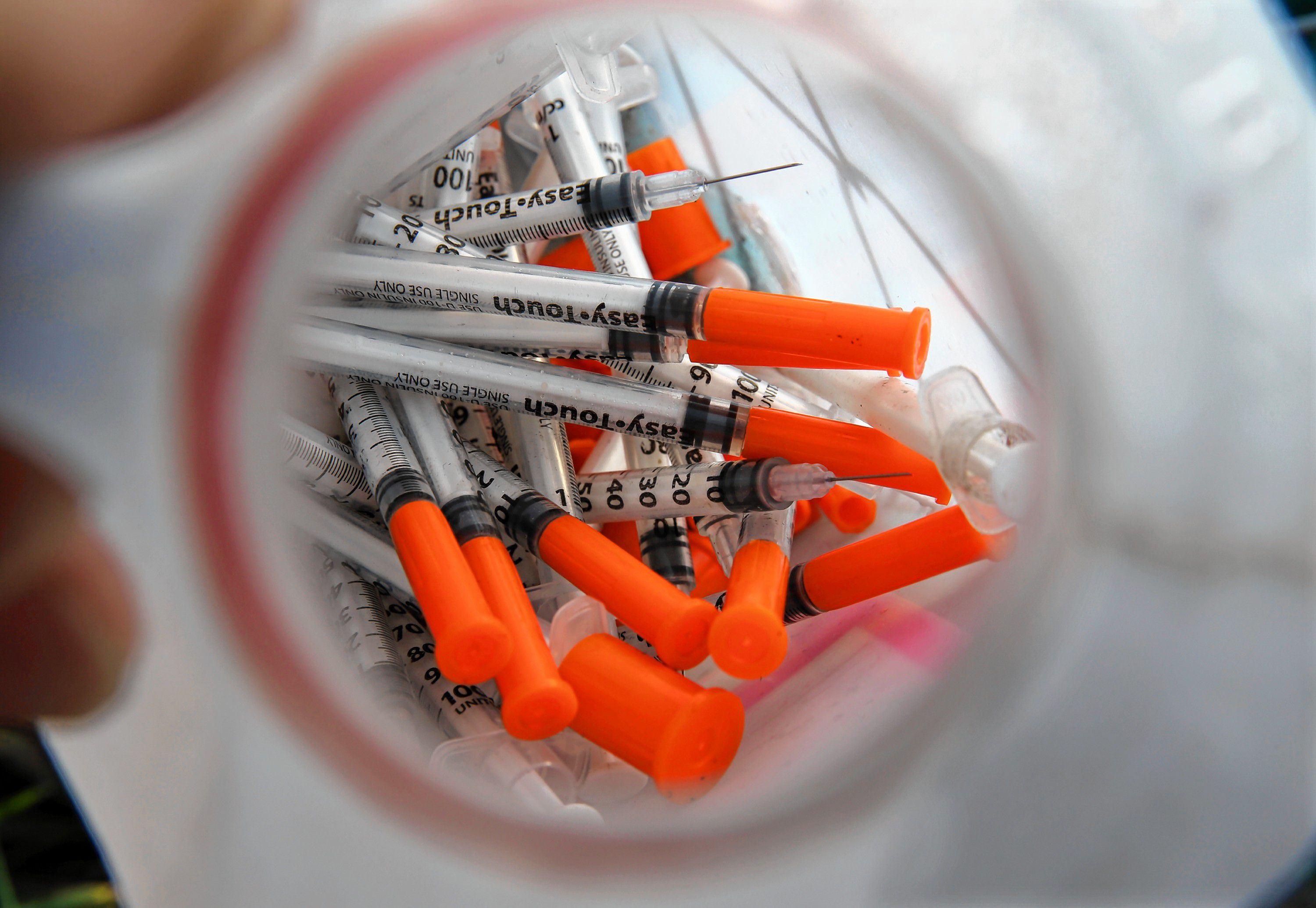 In this Thursday, Oct. 29, 2015 photograph, a jug of used needles to exchange for new is seen  near, Jim "Woods" Ellis in an industrial area of Camden, N.J., as Ellis describes using the drug, naloxone, often known by the brand name Nacran, to reverse an addict's heroin overdose. Naloxone works most of the time, but national statistics arent kept on what happens to people who are revived. Some overdose again soon afterward. Some get treatment and get clean, but limited insurance, high costs and a shortage of spots at treatment centers can be hurdles. (AP Photo/Mel Evans) Mel Evans