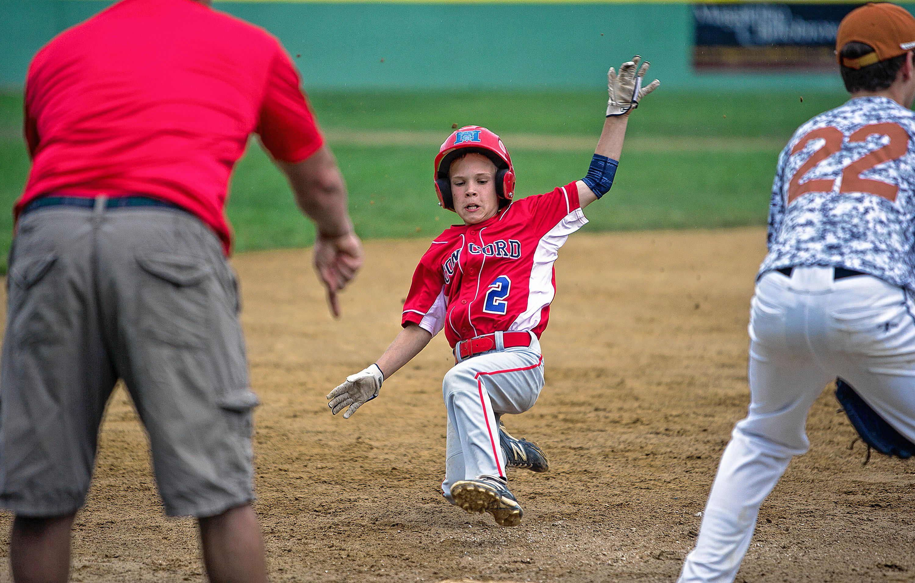 Concord Little League coach Nate Craigue signals for his son Brooks to slide into third base during the first inning at Grappone Park Monday night. Craigue went on to score the first run on a straight steal from third. GEOFF FORESTER