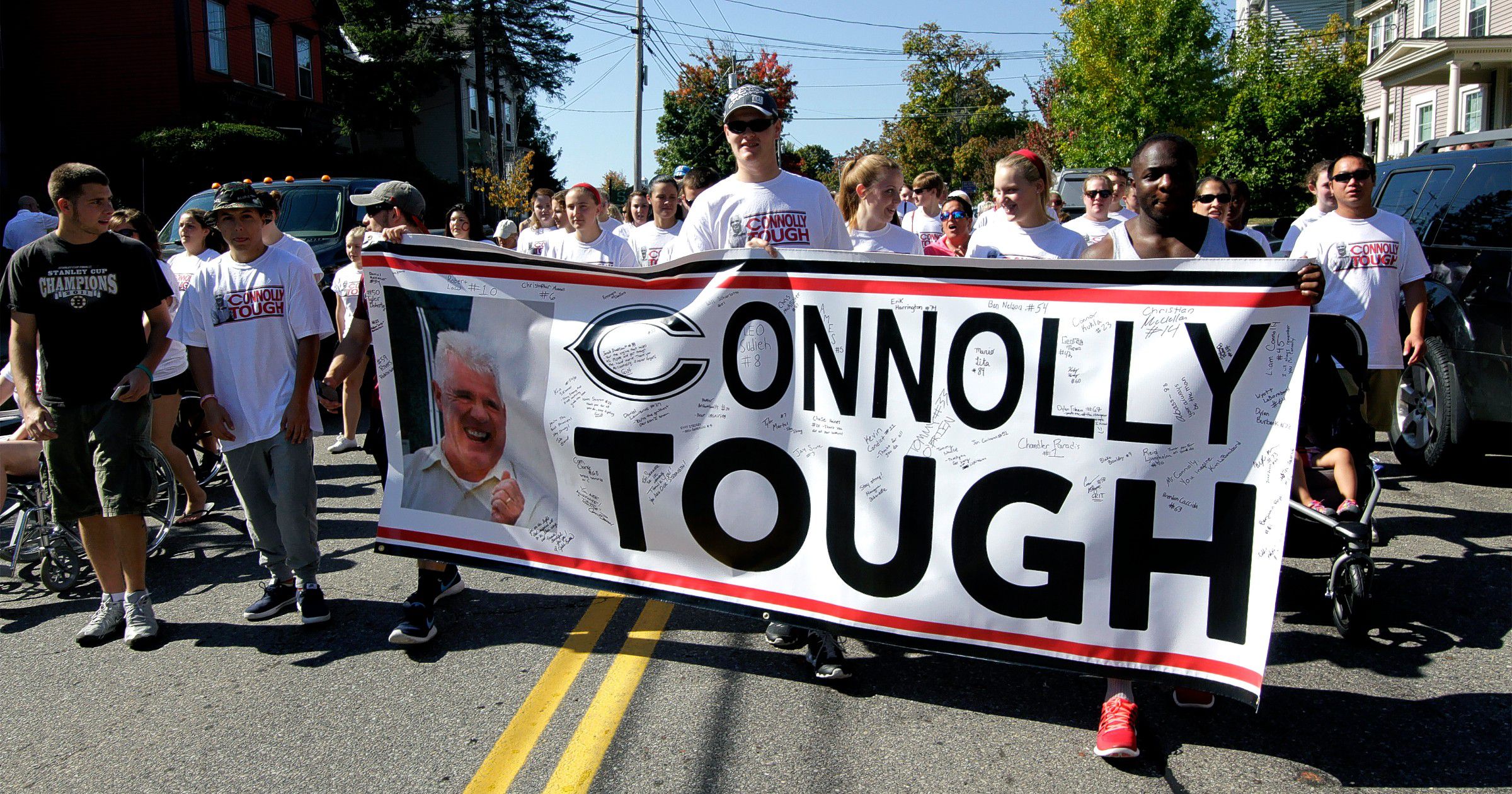 Participants in the ALS walk parade down Pleasant Street Saturday morning in support of Concord High School Principal Gene Connolly.  (GEOFF FORESTER / Monitor staff) Participants hold a “Connolly Tough” banner as they march down Pleasant Street.(GEOFF FORESTER / Monitor staff)     GEOFF FORESTER