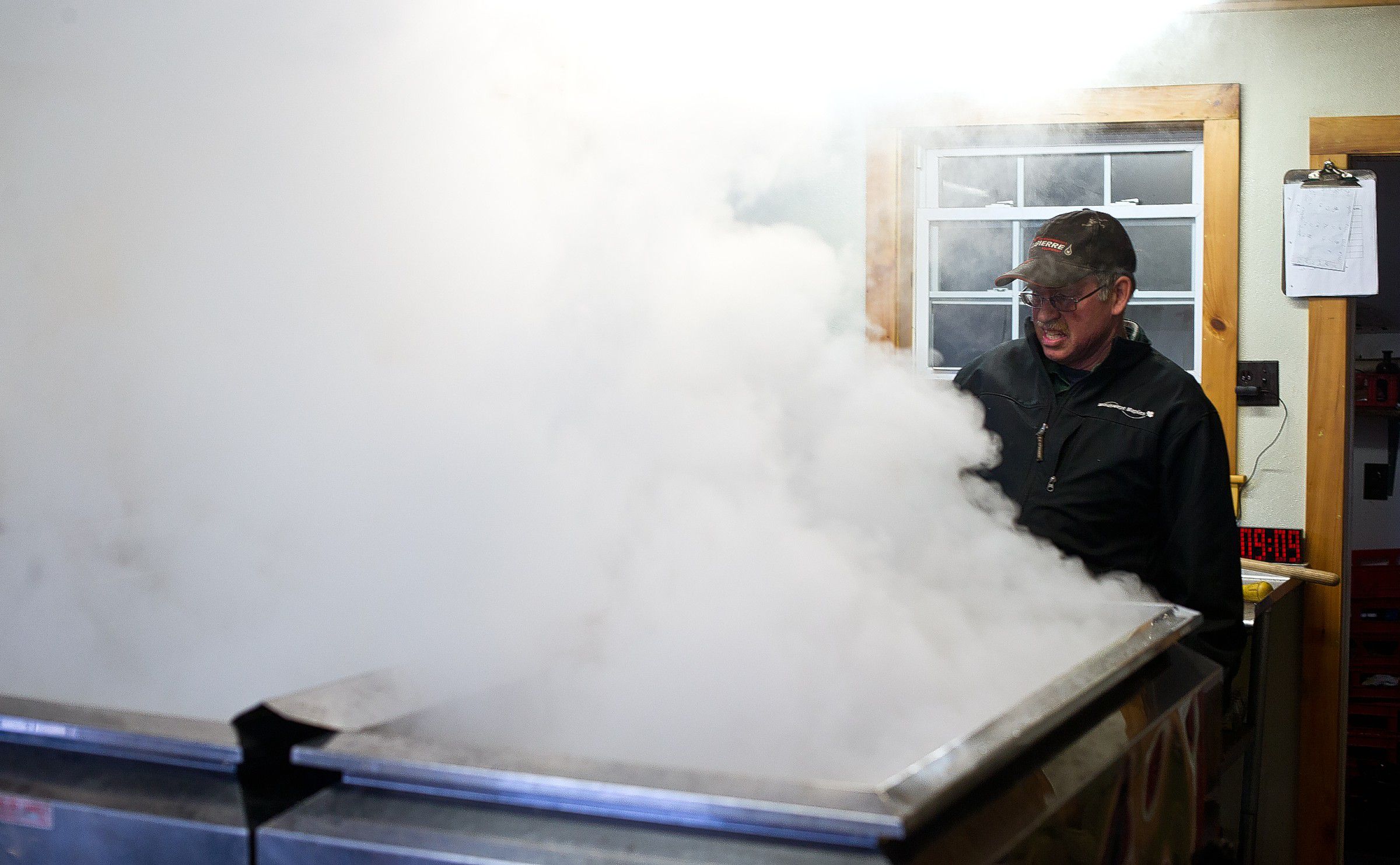 Larry Moore of Windswept Maple Farm in Loudon looks over the maple sryup evaporator as it heats up this week. The warm days have allowed the family farm to start processing syrup in February.  (GEOFF FORESTER / Monitor staff) 