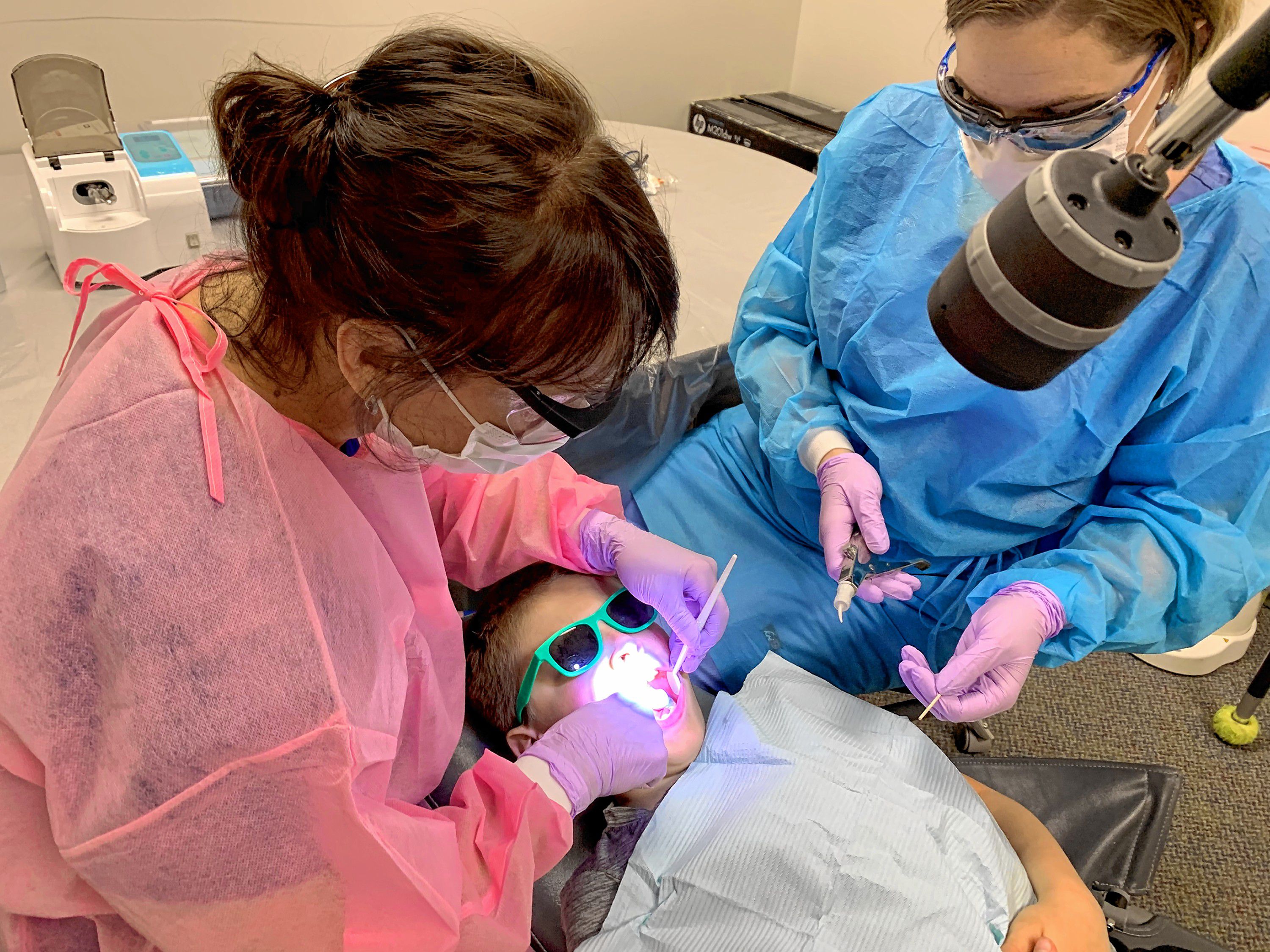 Certified Public Health Hygienist Mary Davis (left) and Dental Assistant Brittani Oldham (right) provide dental care to second grader Brady Humphreys (center) at Penacook Elementary School Wednesday. 