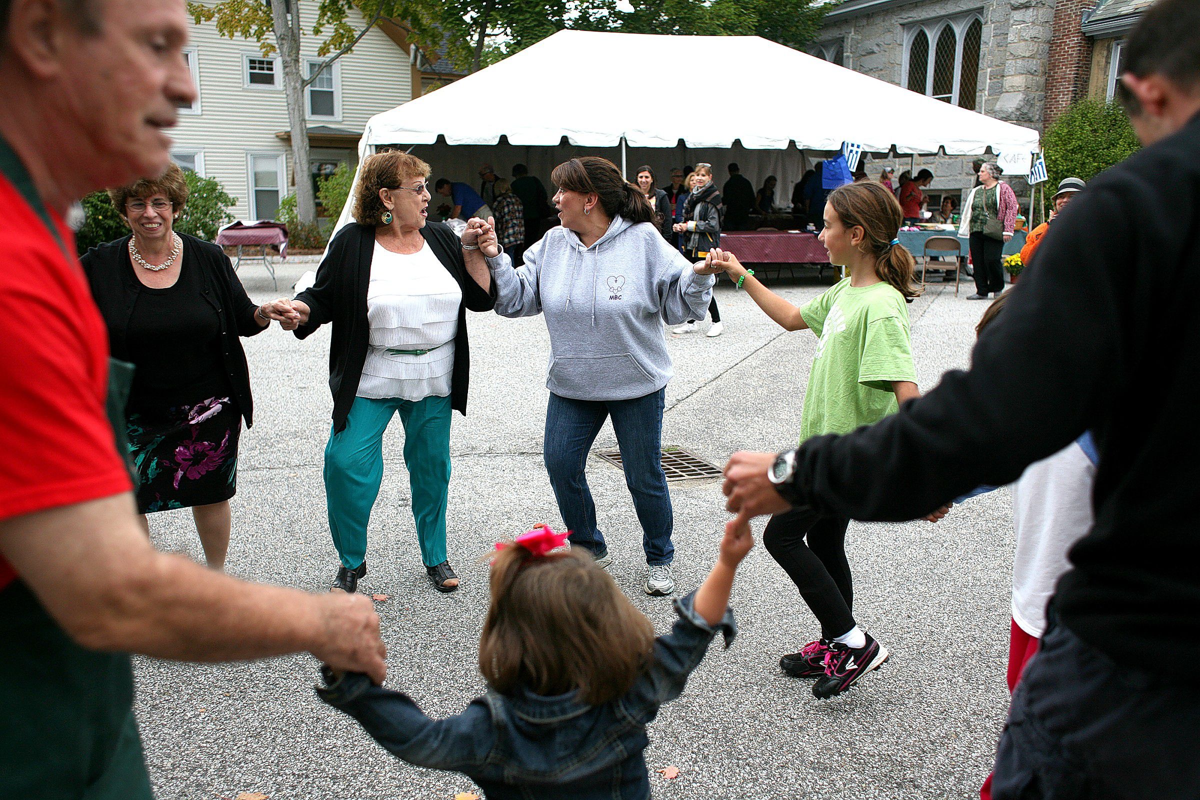 Lorry Hartofelis (center left) of Concord sings a Greek song with fellow church member Barbara Kalioras (center right) as a group dances at the "A Taste of Greece" Greek Festival at Holy Trinity Greek Orthodox Church in Concord on Saturday, Sept. 20, 2014. Also dancing are Helen Charcalis Erskine (back left) of Memphis, Tenn., Alexis Lopes (back right) of Concord, Michael Karathanasis (front left) of Concord, Catherine Laliotis (front center), 1, of Concord, and Andy Laliotis (front right) of Concord. (JULIE BYRD-JENKINS / Monitor staff)  Julie Byrd-Jenkins