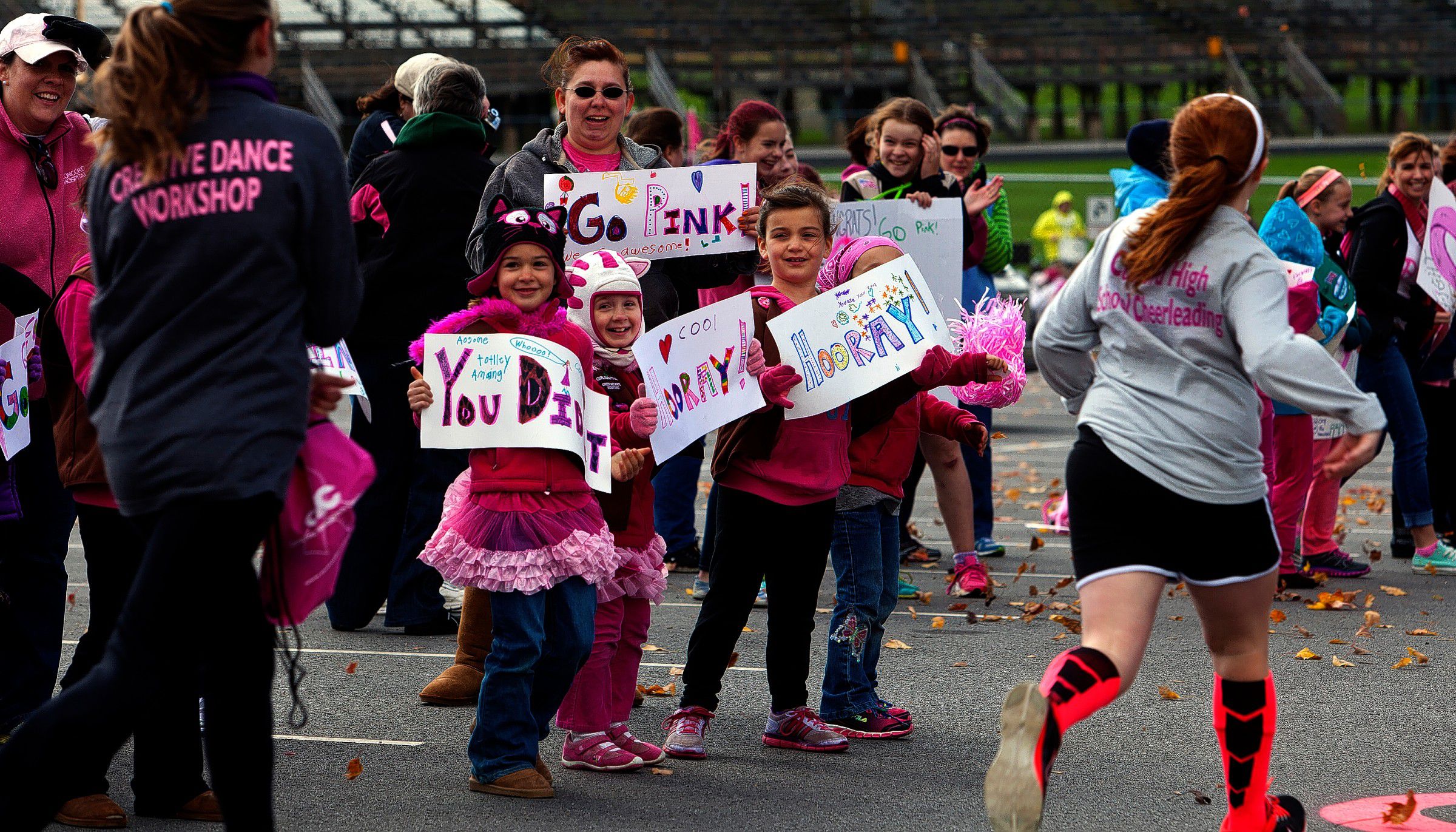 Avery Frazier, 7, left, Ally Moore, 7, center,  and Ramsey Drapeau, 7, along with Amanda Varney in back, hold up signs and greets runners at the Making Strides Against Breast Cancer Walk at the finish line at Memorial Field Sunday, October 19, 2014.  (GEOFF FORESTER / Monitor staff) Avery Frazier (left), 7, Ally Moore (center), 7, and Ramsey Drapeau, 7, along with Amanda Varney (in back), hold signs and greet runners at the Making Strides Against Breast Cancer walk at Memorial Field in Concord yesterday. 