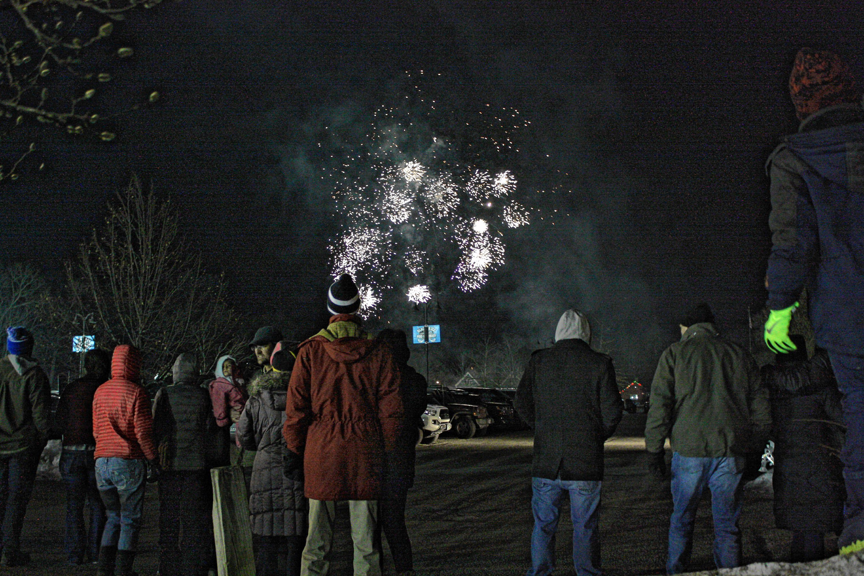 People watch the fireworks show over the baseball field at White Park during the 1883 Black Ice Pond Hockey Championship on Jan. 26, 2019. 