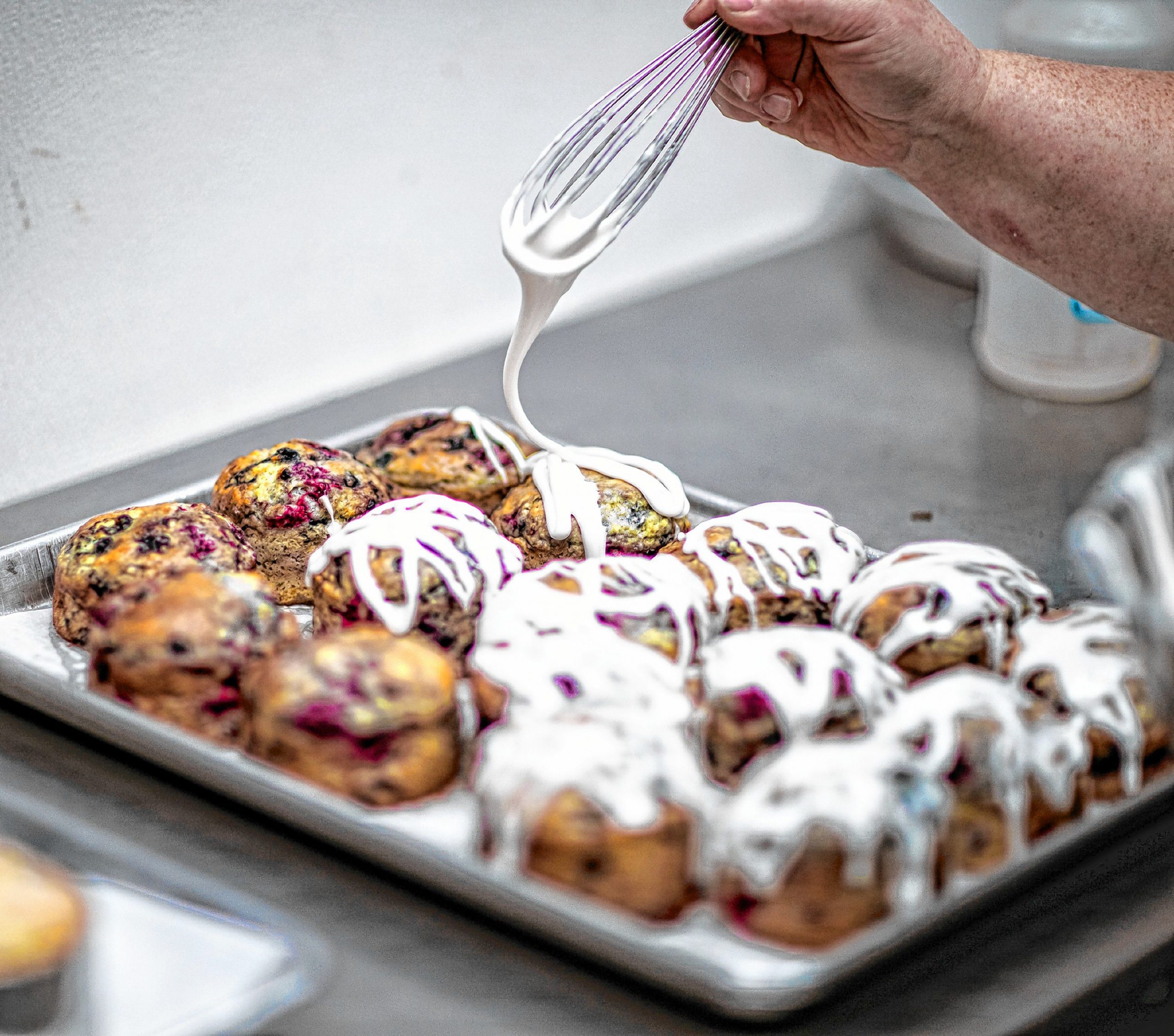 Crust and Crumb owner Alison Ladman puts a drizzle topping on top of the three berry muffins at the baking company on North Main Street in Concord. 