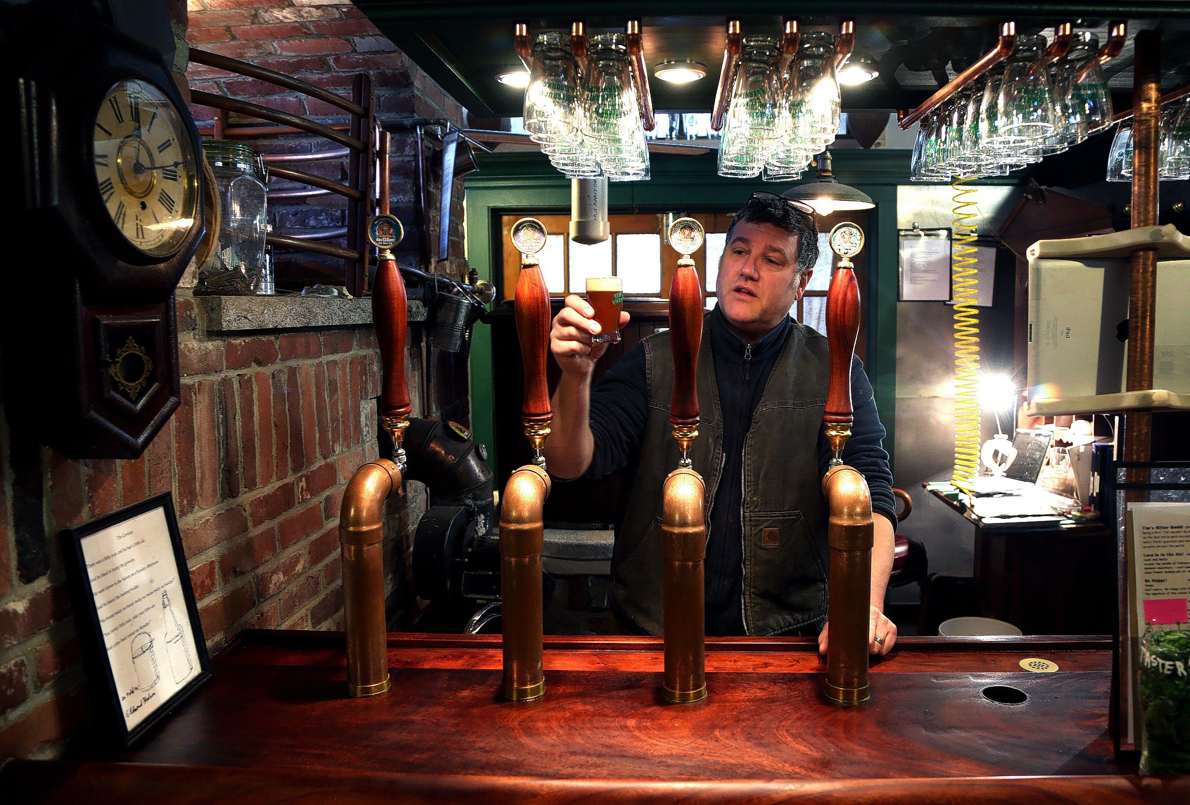 Steve Allman, brewer and owner of Canterbury Aleworks holds up a sample of one of his brews. (GEOFF FORESTER / Monitor staff) Steve Allman, brewer and owner of Canterbury Aleworks, holds up a sample of one of his brews. Below: This whimsical sign hangs outside the entrance to the brewery. 