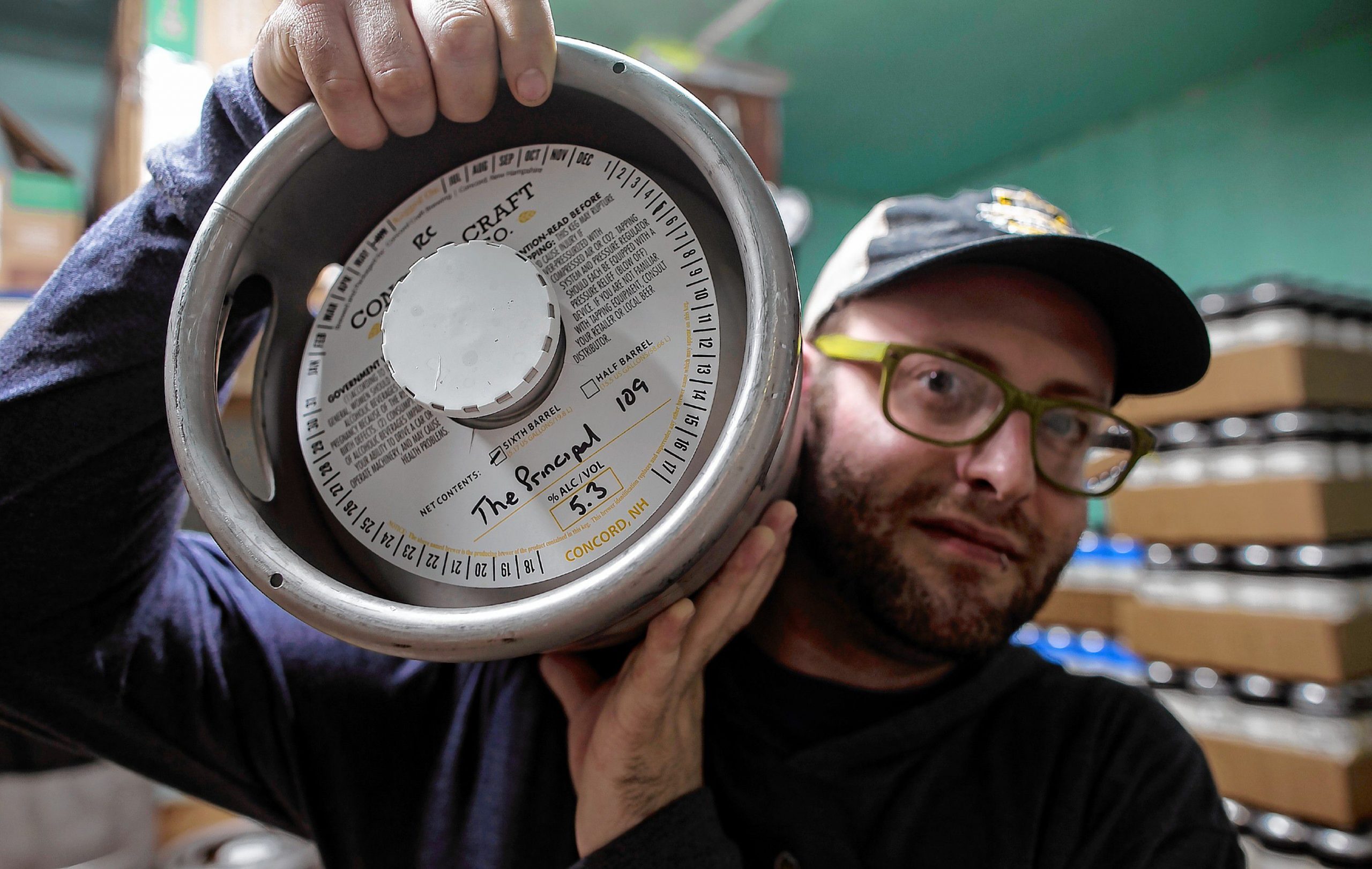 Noah Brochu, tasting room manager for Concord Craft brewing holds a mini-keg of the new pale ale, âThe Principal,â in Connollyâs honor this month to raise money for the  ALS Therapy Development Institute.  