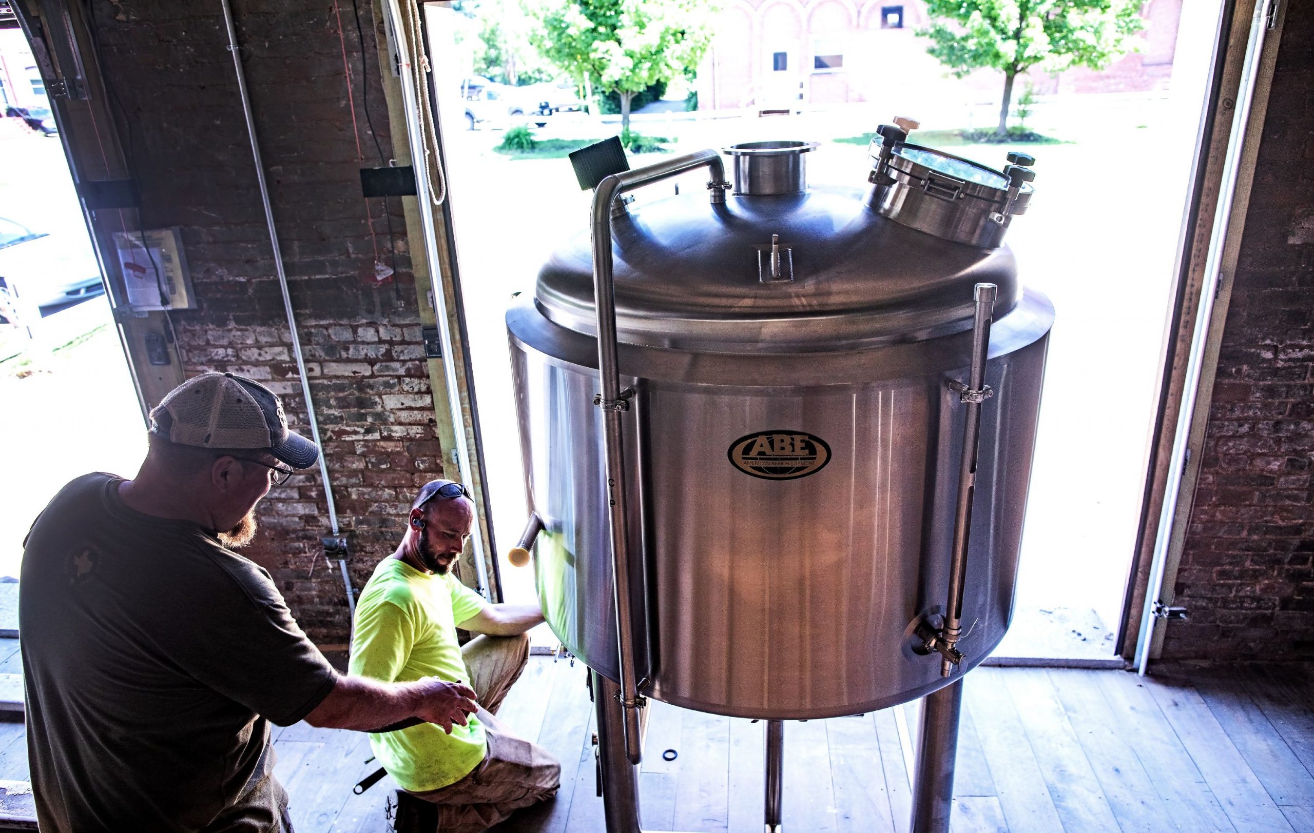 Damon Lewis (left), co-owner of the new Vulgar Brewery in downtown Franklin, helps Russell Belmer of Shaughnessy Rigging of Deerfield move a seven barrel boil kettle into the new brewery on Monday, July 1, 2019. The brewery is one of the places in Franklin getting financing from Franklin Savings Bank. GEOFF FORESTER