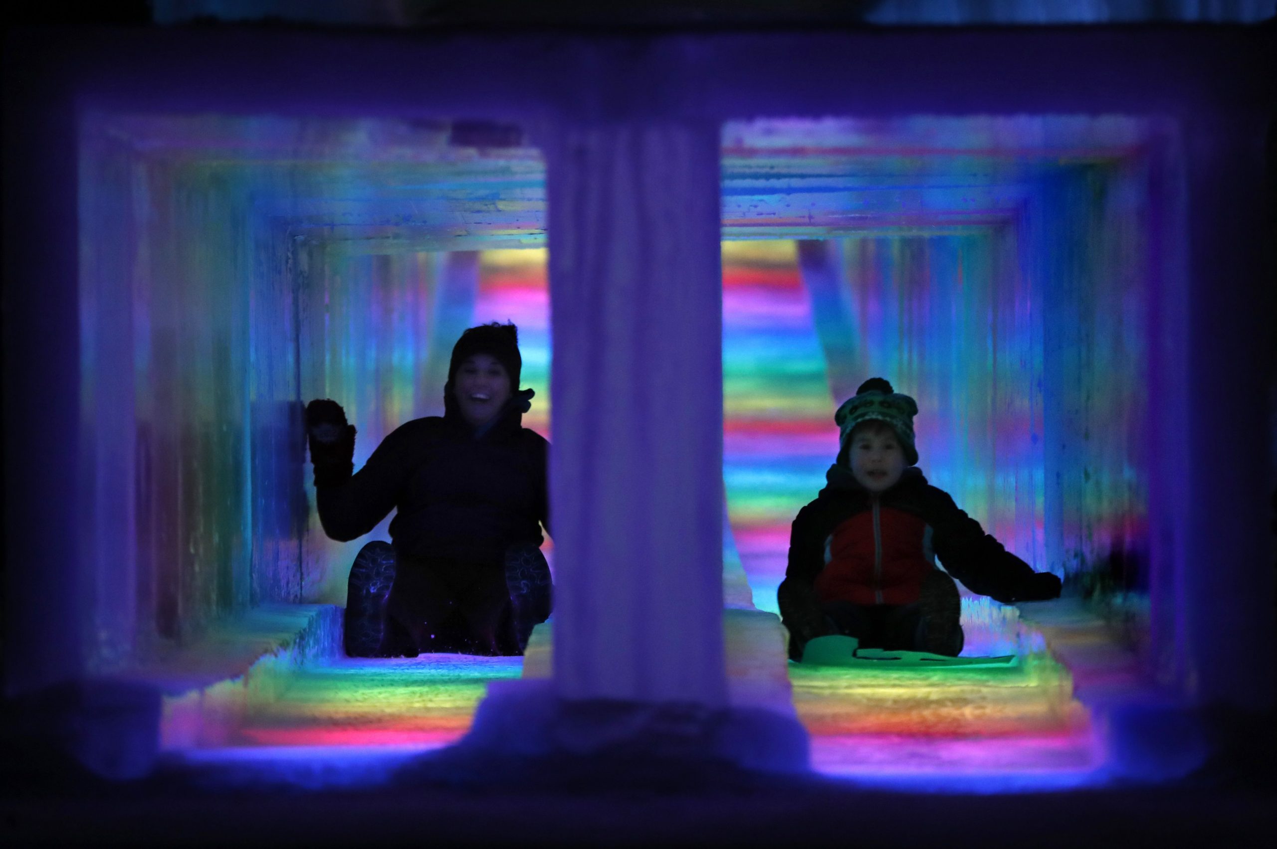 In this Friday, Jan. 25, 2019 photo, visitors race down the side-by-side tunnels of a 97-foot ice slide at Ice Castles in North Woodstock, N.H. The winter wonderland is one of six in North America. (AP Photo/Robert F. Bukaty)  Robert F. Bukaty