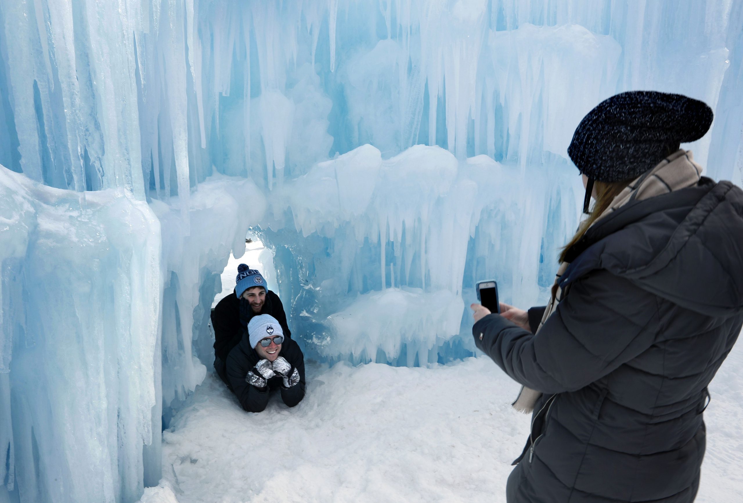 In this Saturday, Jan. 26, 2019 photo, visitors pose for a photo in a tunnel at Ice Castles in North Woodstock, N.H. With a seemingly endless variety of photo-ops, most visitors have a hard time putting their cameras down. (AP Photo/Robert F. Bukaty)  Robert F. Bukaty