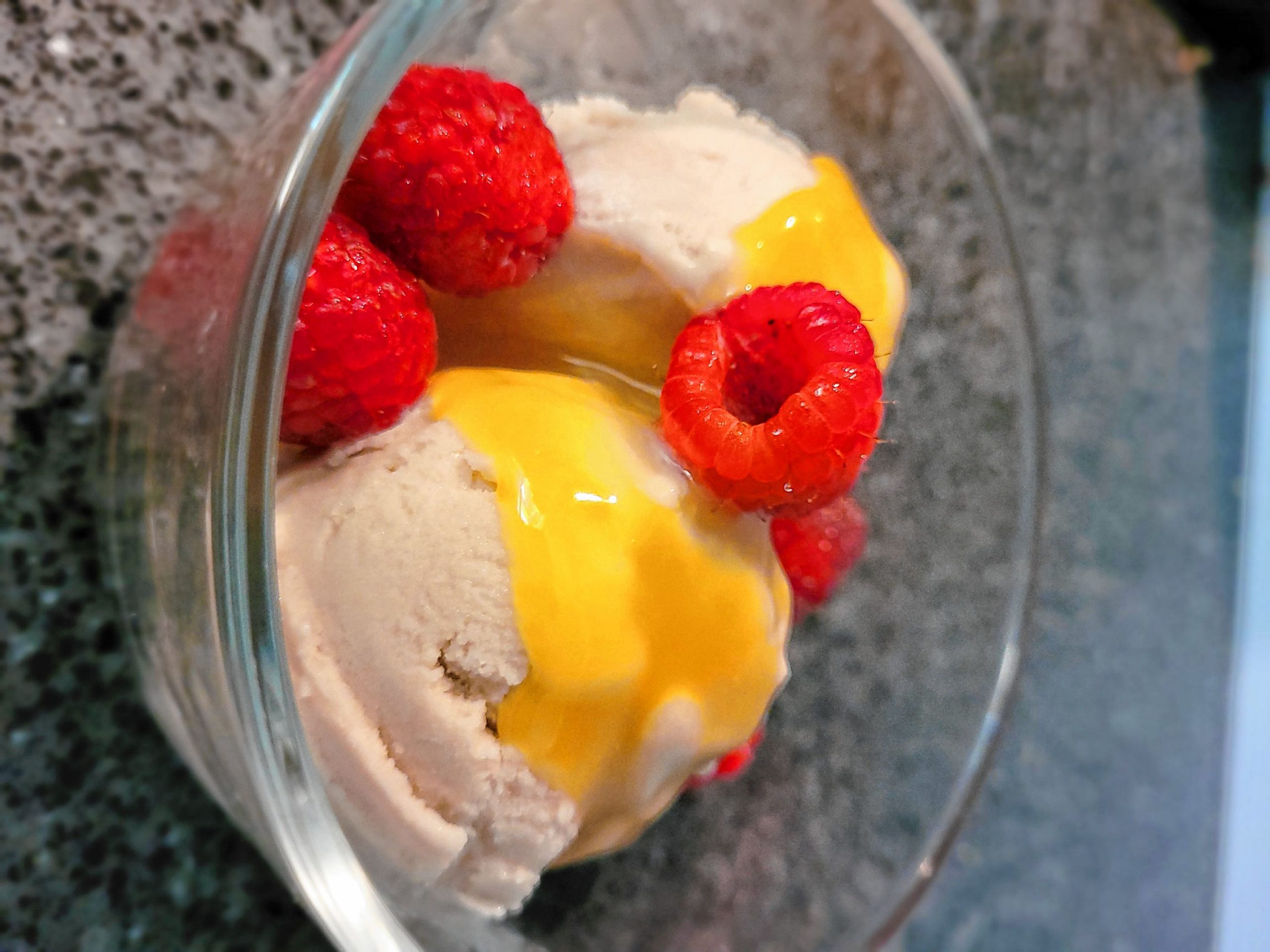 Vegan vanilla ice cream with lemon curd and raspberries.