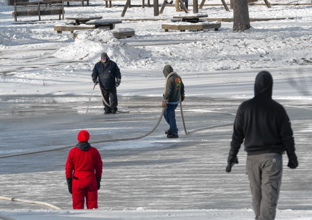 Concord Parks and Recreation workers pour water on the pond at White Park to smooth out the surface in anticipation of skating and the Black Ice Tournament later this month. GEOFF FORESTER