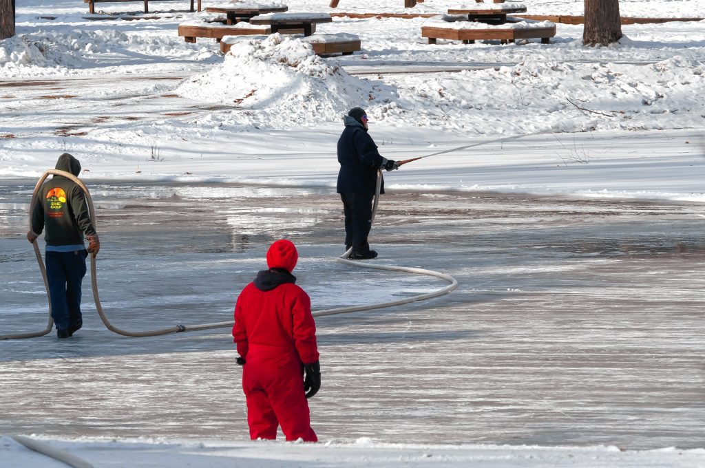 Concord Parks and Recreation workers pour water on the pond at White Park to smooth out the surface in anticipation of skating and the Black Ice Tournament later this month.