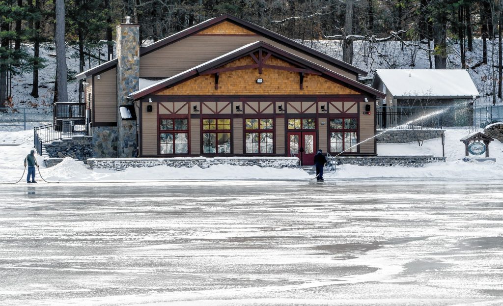 Concord Parks and Recreation workers pour water on the pond at White Park to smooth out the surface in anticipation of skating and the Black Ice Tournament later this month. GEOFF FORESTER