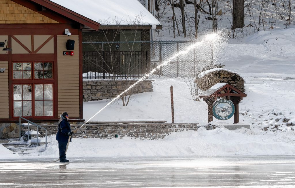 Concord Parks and Recreation workers pour water on the pond at White Park to smooth out the surface in anticipation of skating and the Black Ice Tournament later this month. GEOFF FORESTER