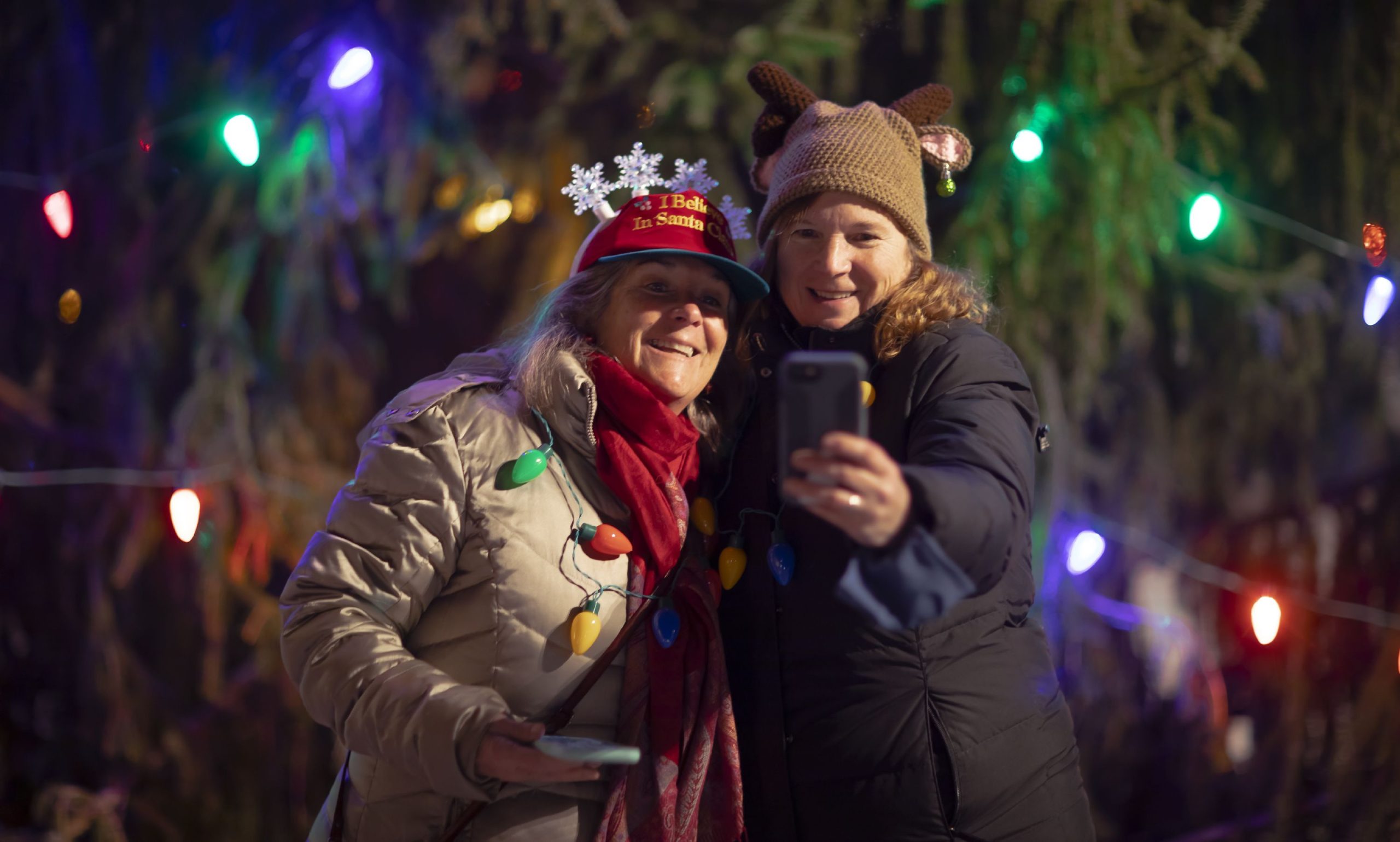 Anne White (left) and Debbie Camejo both from Bridgewater, New Hampshire take a selfie in front of the Christmas tree on City Plaza in front of the State House at the start of Midnight Merriment on Friday night. 