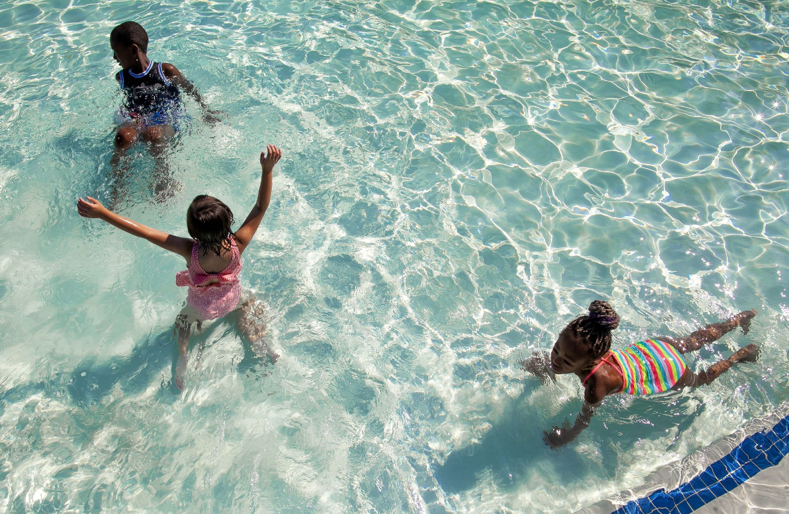 Amiyah Adair, 6, (center) and her best friend, Therenna Conteh swim in the wading pool along with Therennaâs brother, Konson at Rolfe Park on Wednesday afternoon, July 20, 2022. The pool stayed open until 8 p.m. The heat wave in the area is predicted through the weekend. 