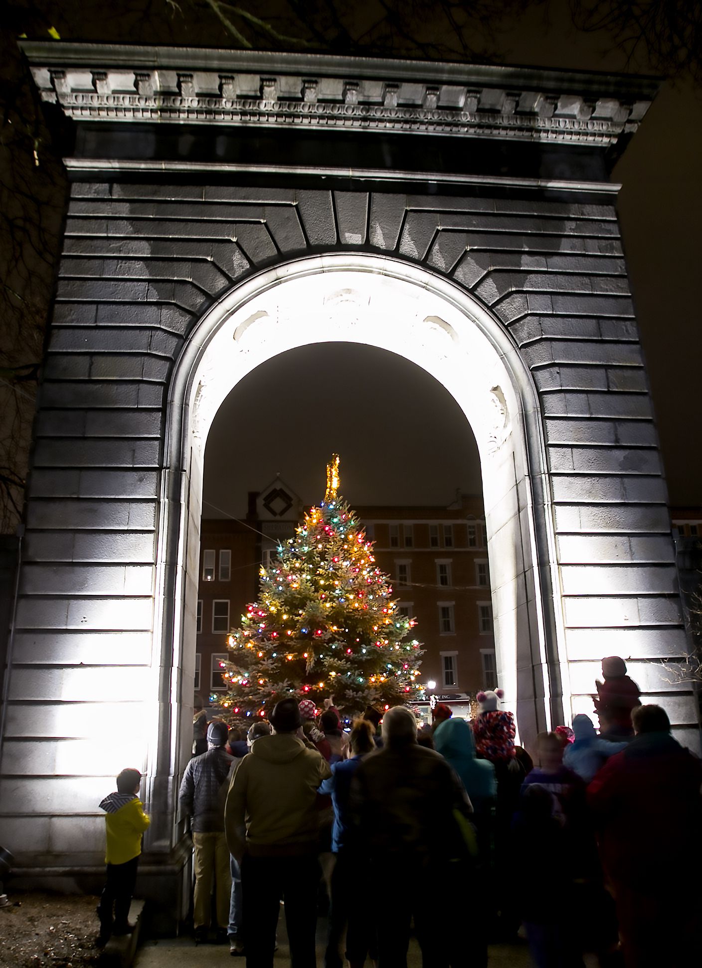 People watch from underneath the State House arch Friday night as the 30th annual Christmas tree lighting capped off a night of festivites. Santa Claus arrived via the Concord fire ladder truck and animal rides around the Park Street to Capitol Street and the evening finished with fireworks over Main Street. 